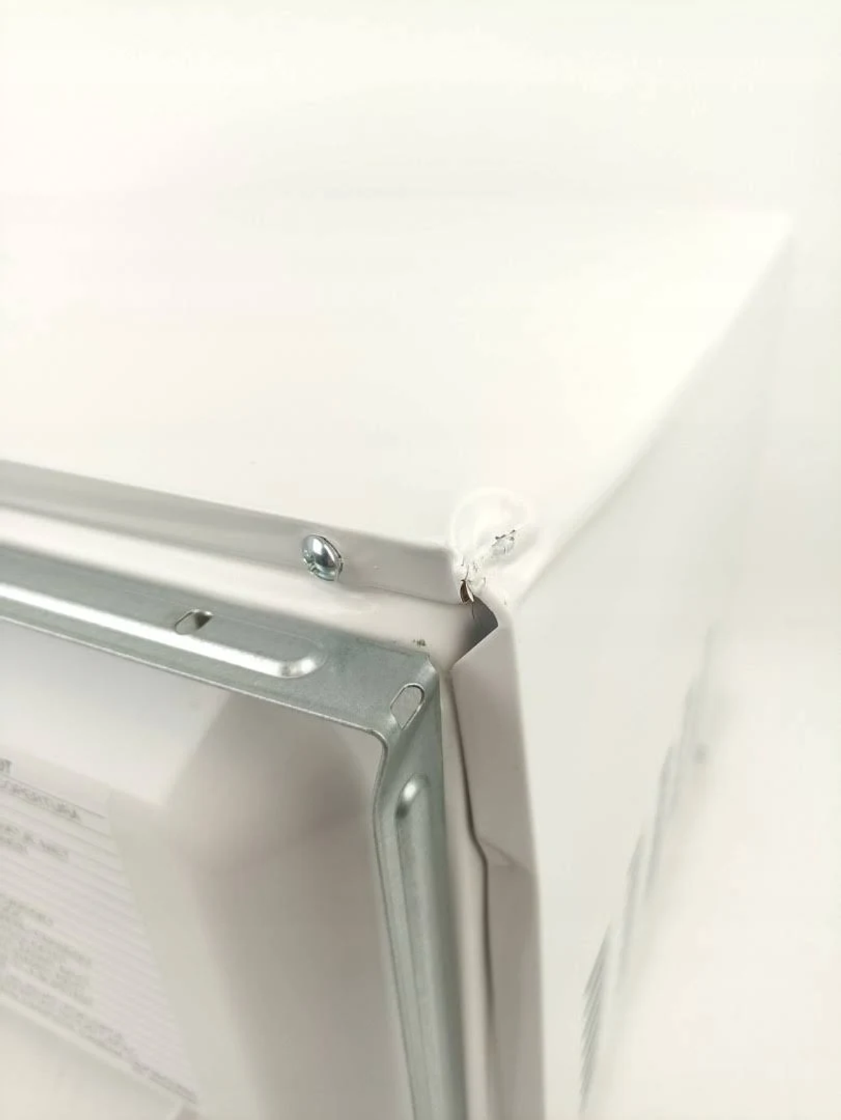 Primer plano de un horno microondas blanco que muestra el lateral y la parte superior. Se ve una esquina metálica.