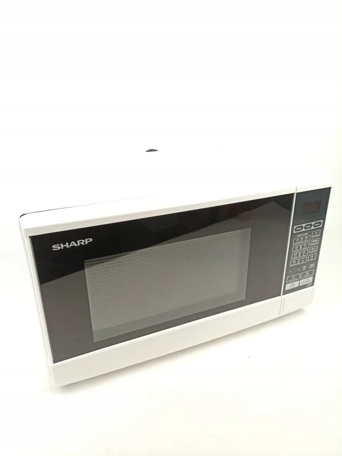 Un horno microondas Sharp blanco se presenta con la puerta cerrada sobre una superficie blanca.