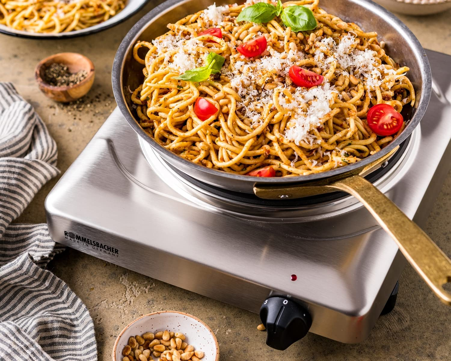 Pasta in una padella su un fornello portatile con ingredienti a lato.