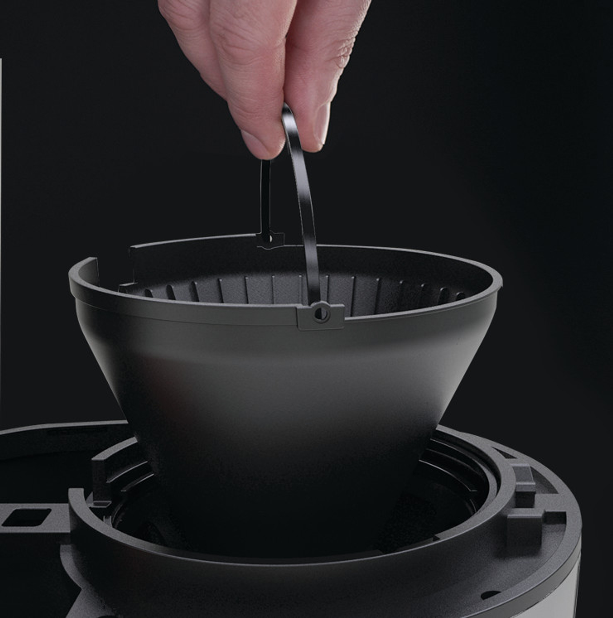 Mano sosteniendo la cesta del filtro de una cafetera.