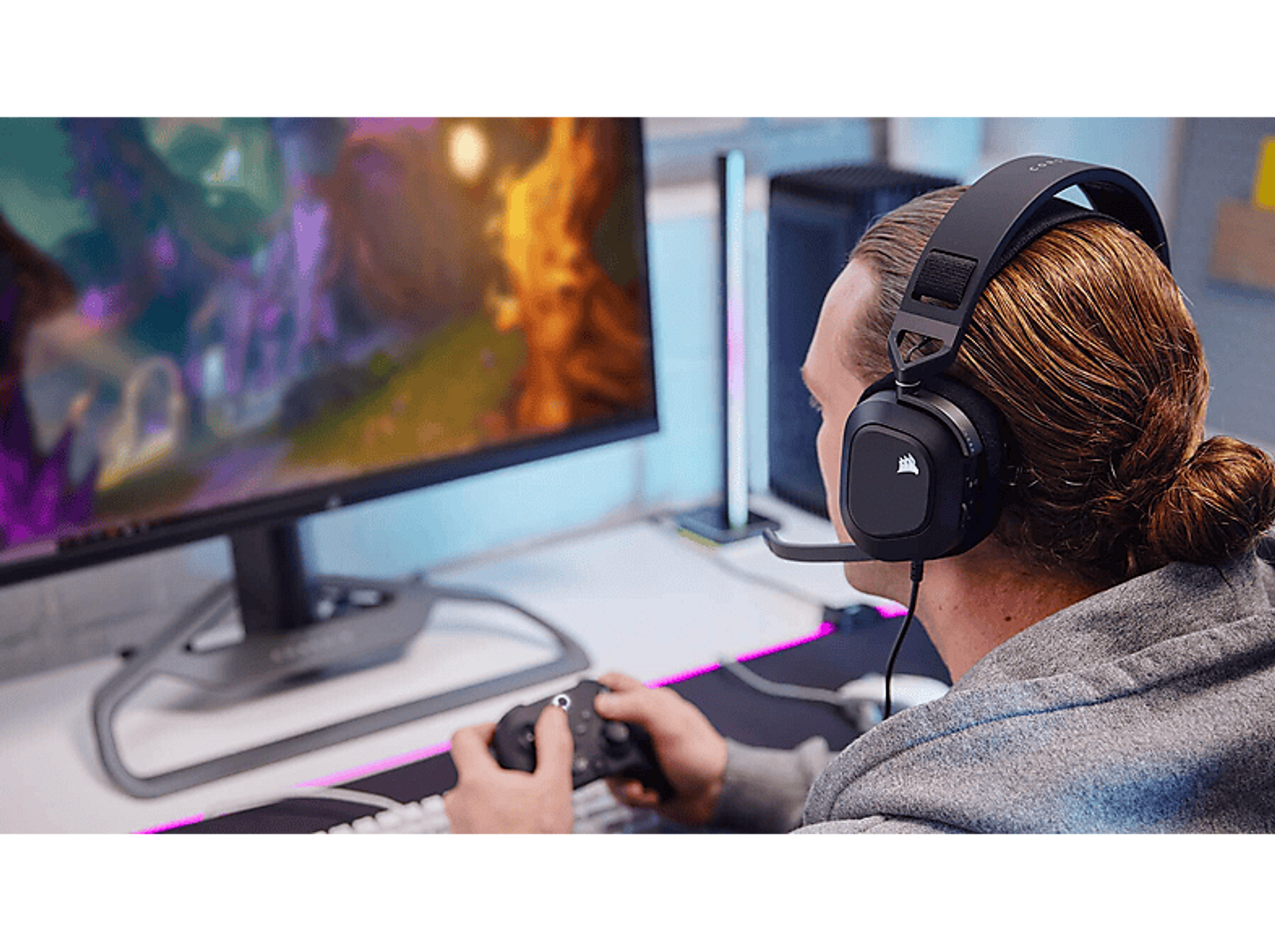 Osoba w czarnych słuchawkach, trzymająca kontroler, grająca.