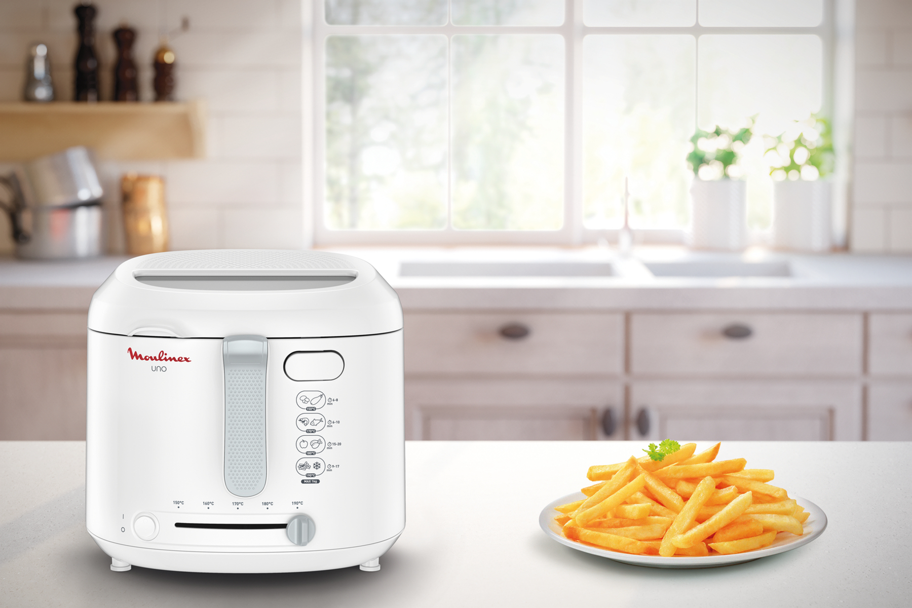 Friteuse Moulinex Uno blanche et une assiette de frites sur un comptoir de cuisine.