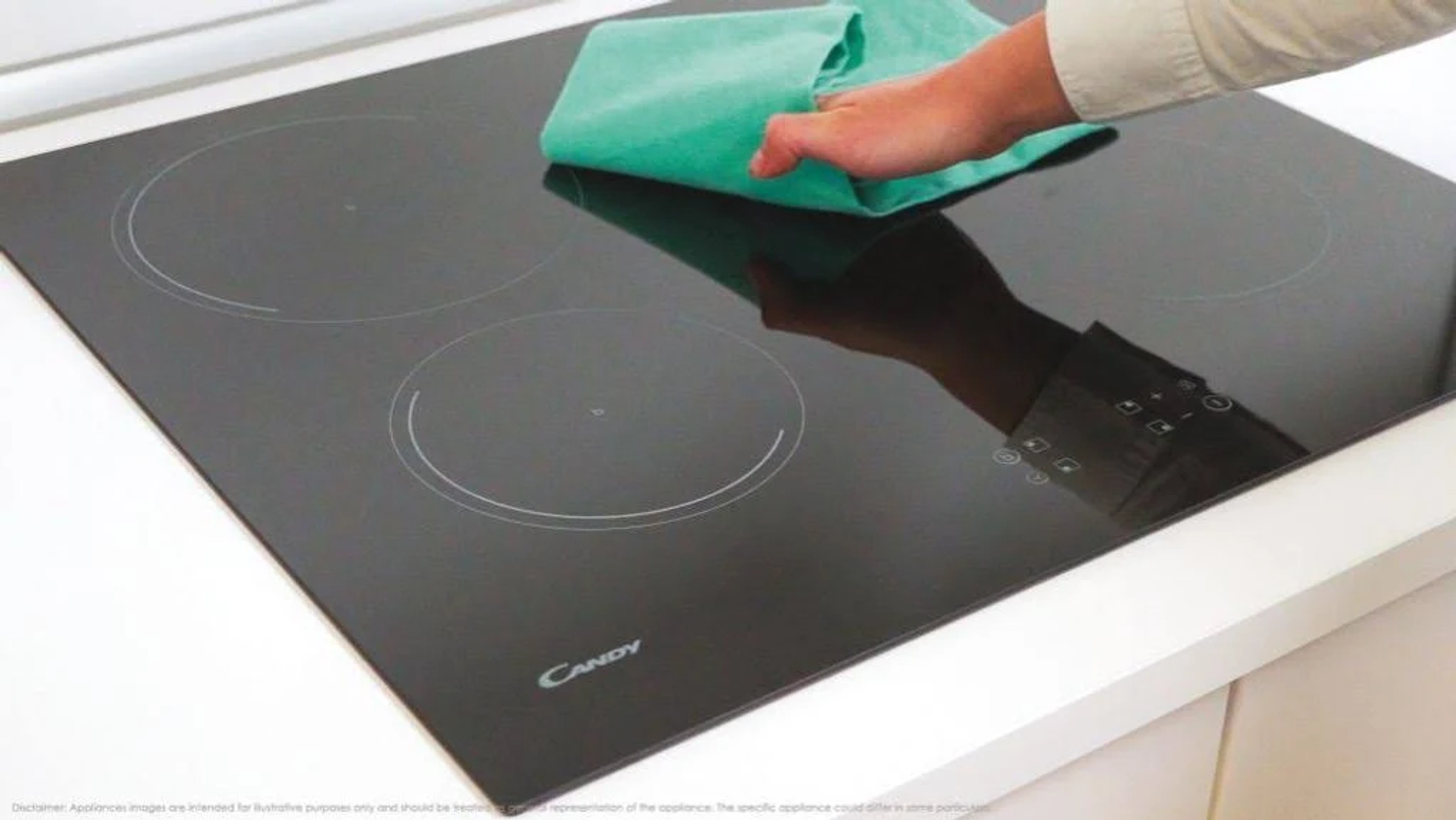 Ręka osoby czyści czarną płytę grzewczą zieloną szmatką.