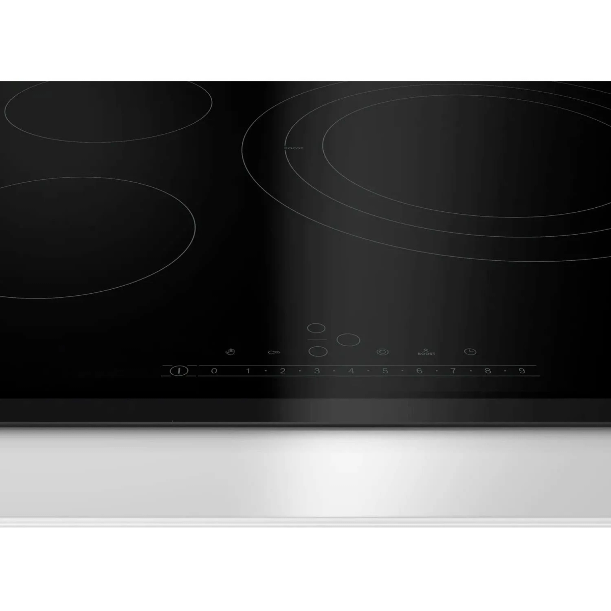 Encimera negra brillante con cuatro zonas de cocción circulares y un panel de control. La superficie refleja la luz.