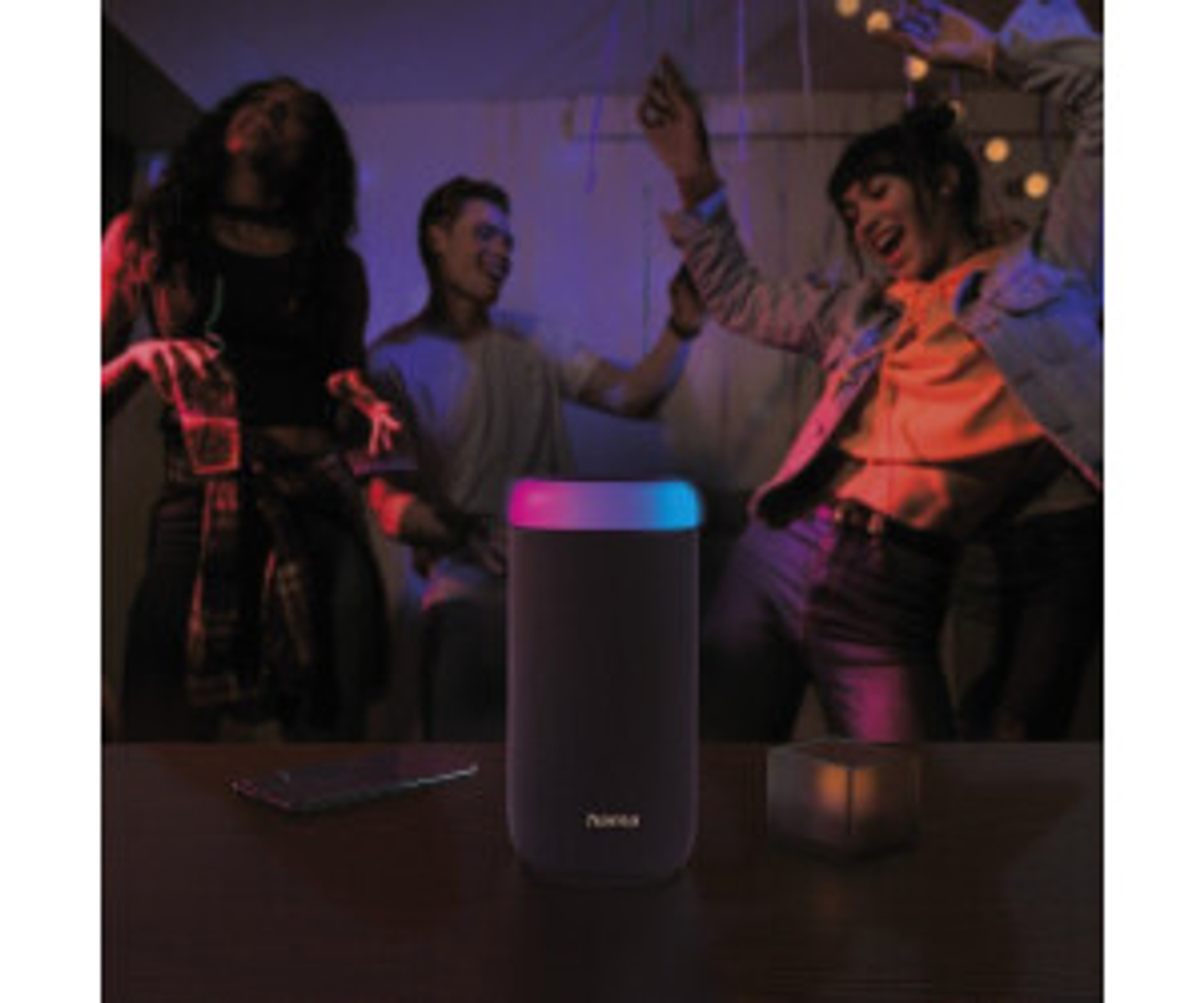 Scena imprezy z tańczącymi ludźmi w pobliżu głośnika ze światłem gradientowym i smartfonem.