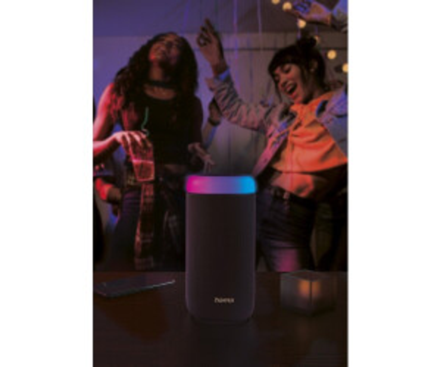 Czarny głośnik z kolorowymi światłami na imprezie. Dwie osoby tańczą w tle.