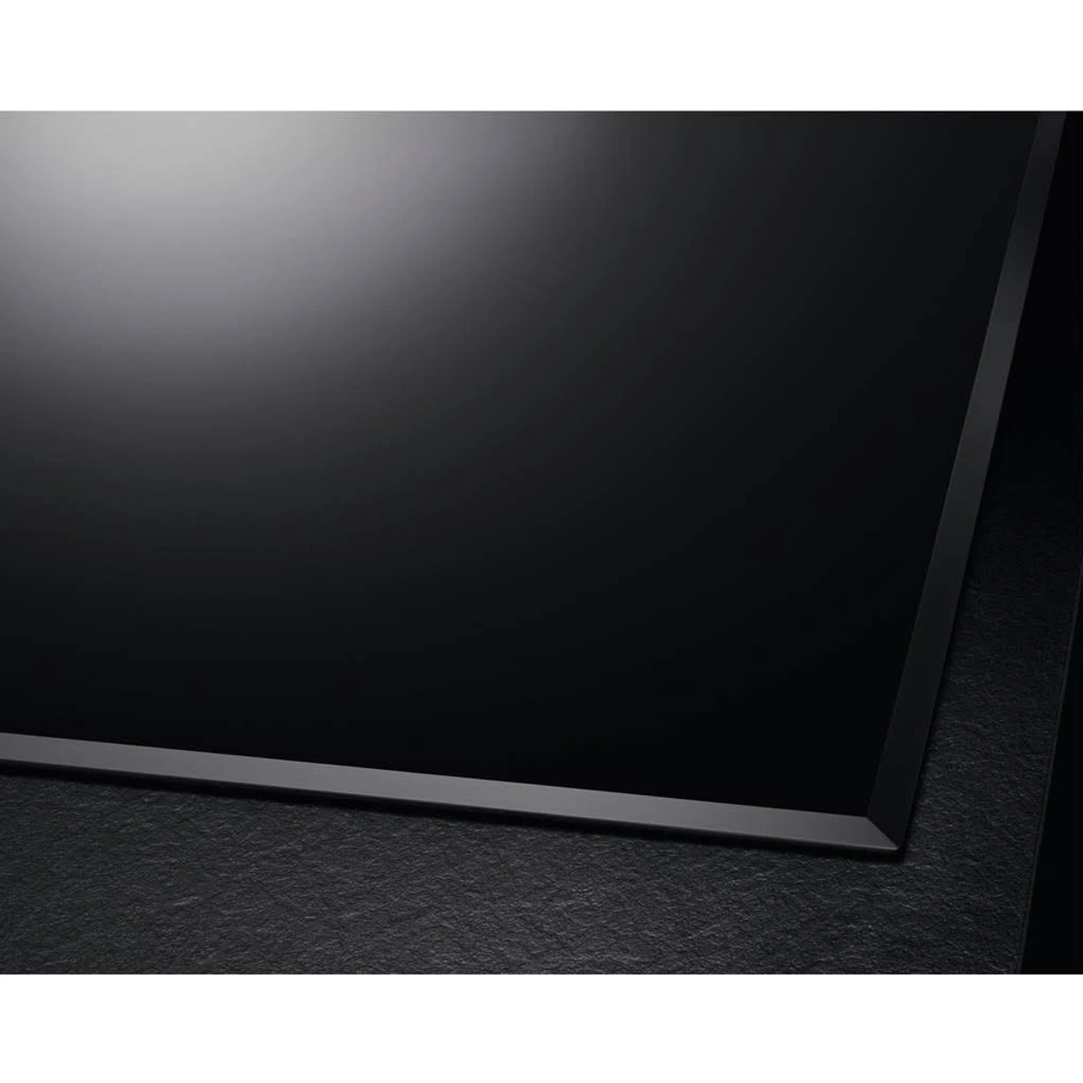 Primo piano di un piano cottura nero ed elegante. La superficie è liscia e riflettente.