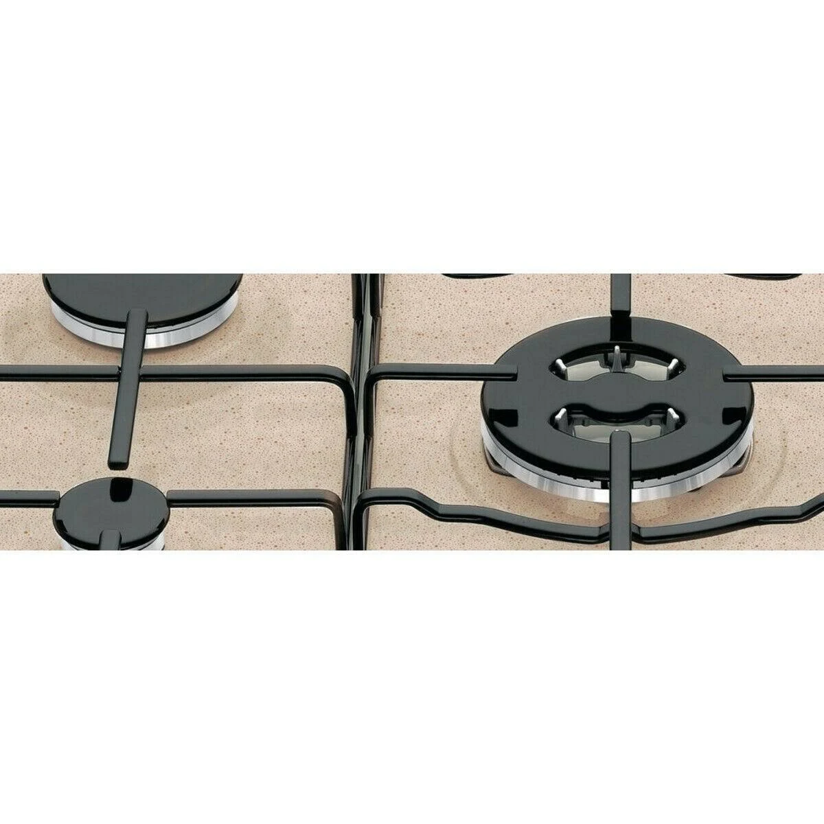 Zbliżenie palników kuchenki gazowej, czarne ze srebrnymi pierścieniami, na beżowej, nakrapianej powierzchni.