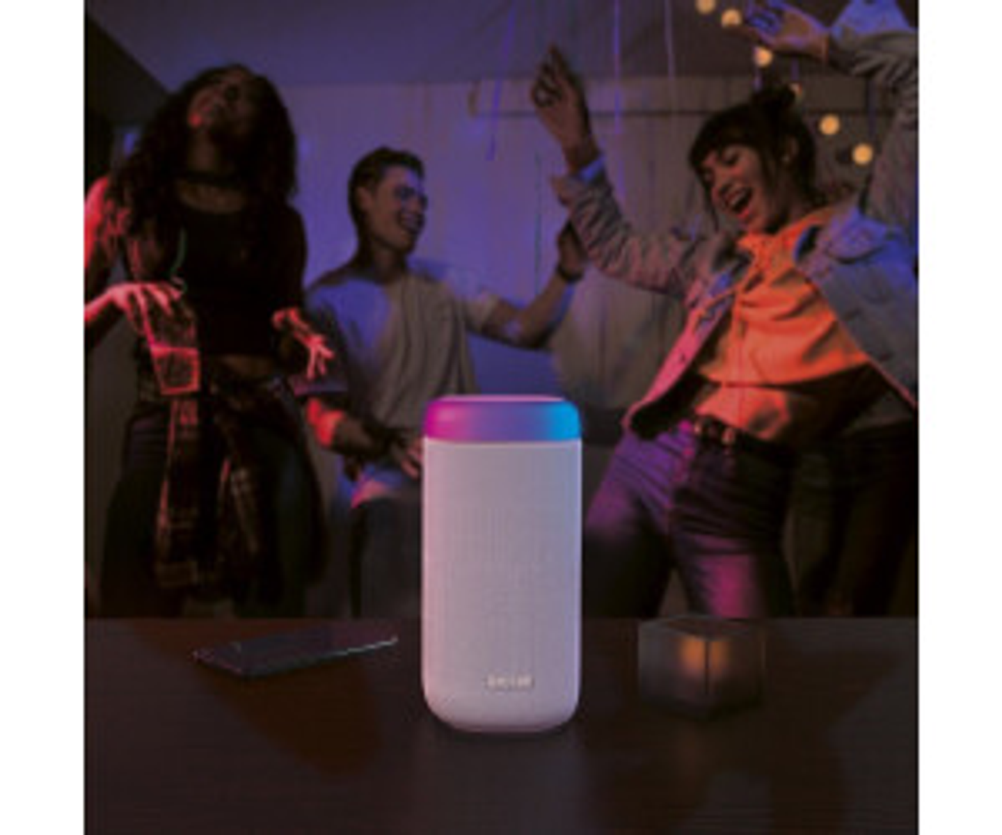 Scena imprezy z głośnikiem, tańczącymi ludźmi i kolorowym oświetleniem.