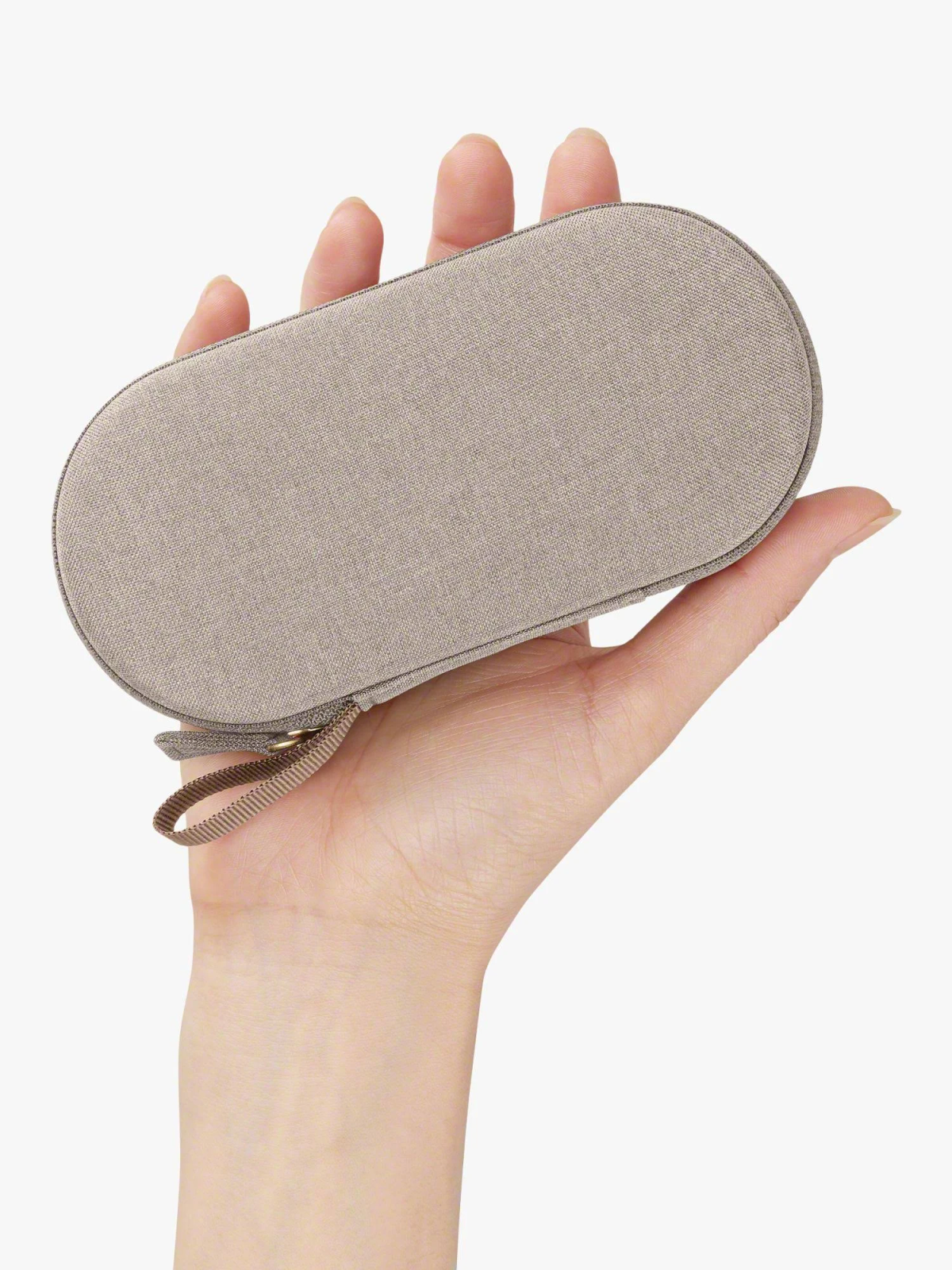 A hand holds a beige, oval-shaped case with a small loop on the side.
