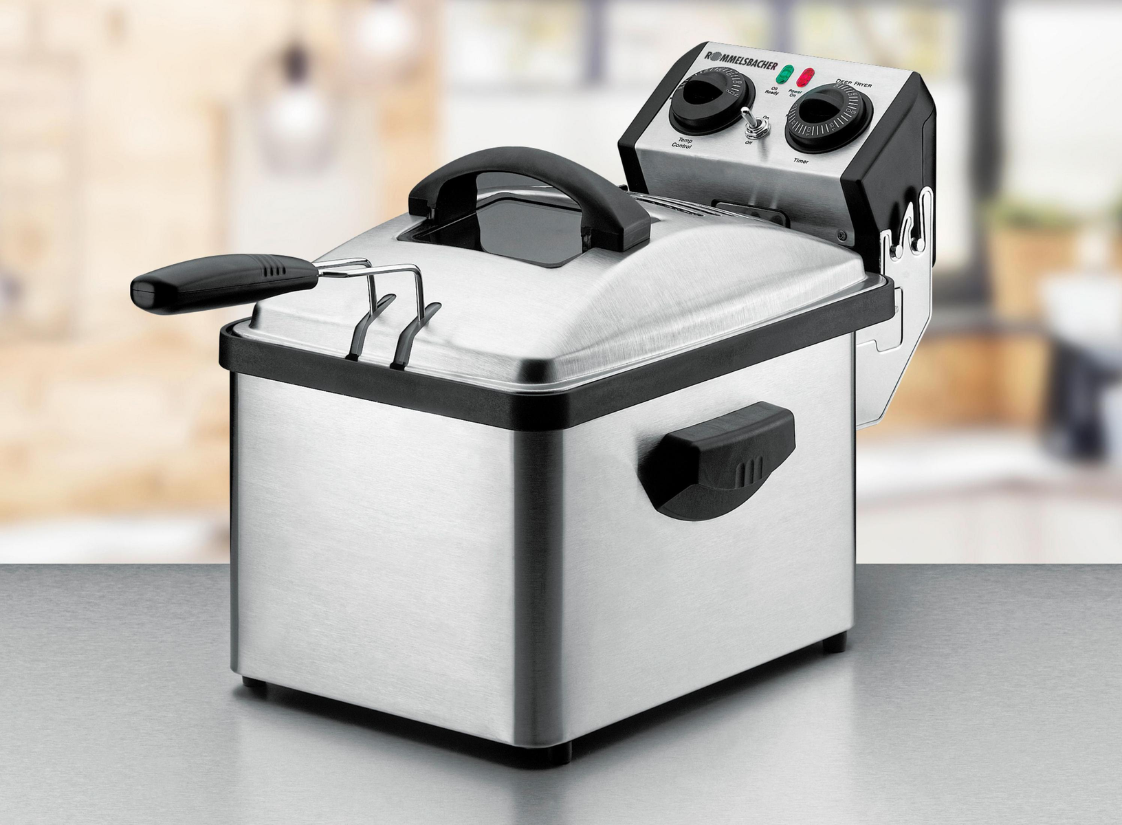 Frytownica ze stali nierdzewnej z czarnym uchwytem i elementami sterującymi na górze, na metalowej powierzchni.