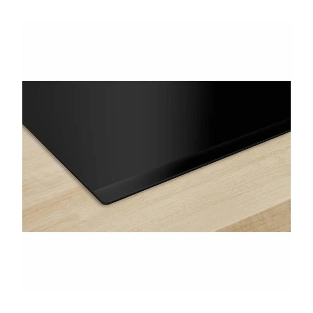 Czarna płyta grzewcza na drewnianej powierzchni. Płyta jest równo z drewnem.