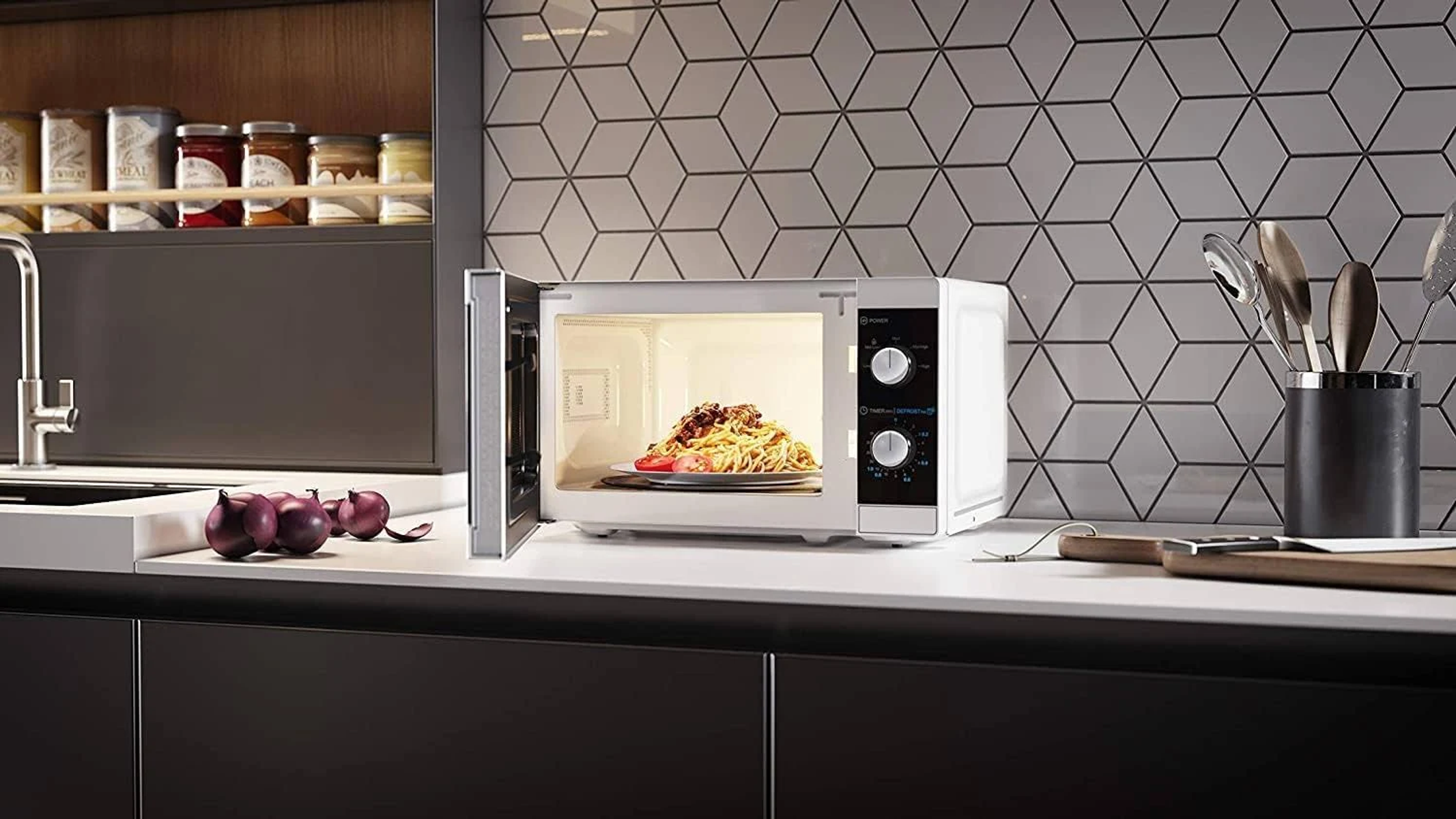 Magnetron met open deur, toont een bord met eten. Op een aanrecht met uien.