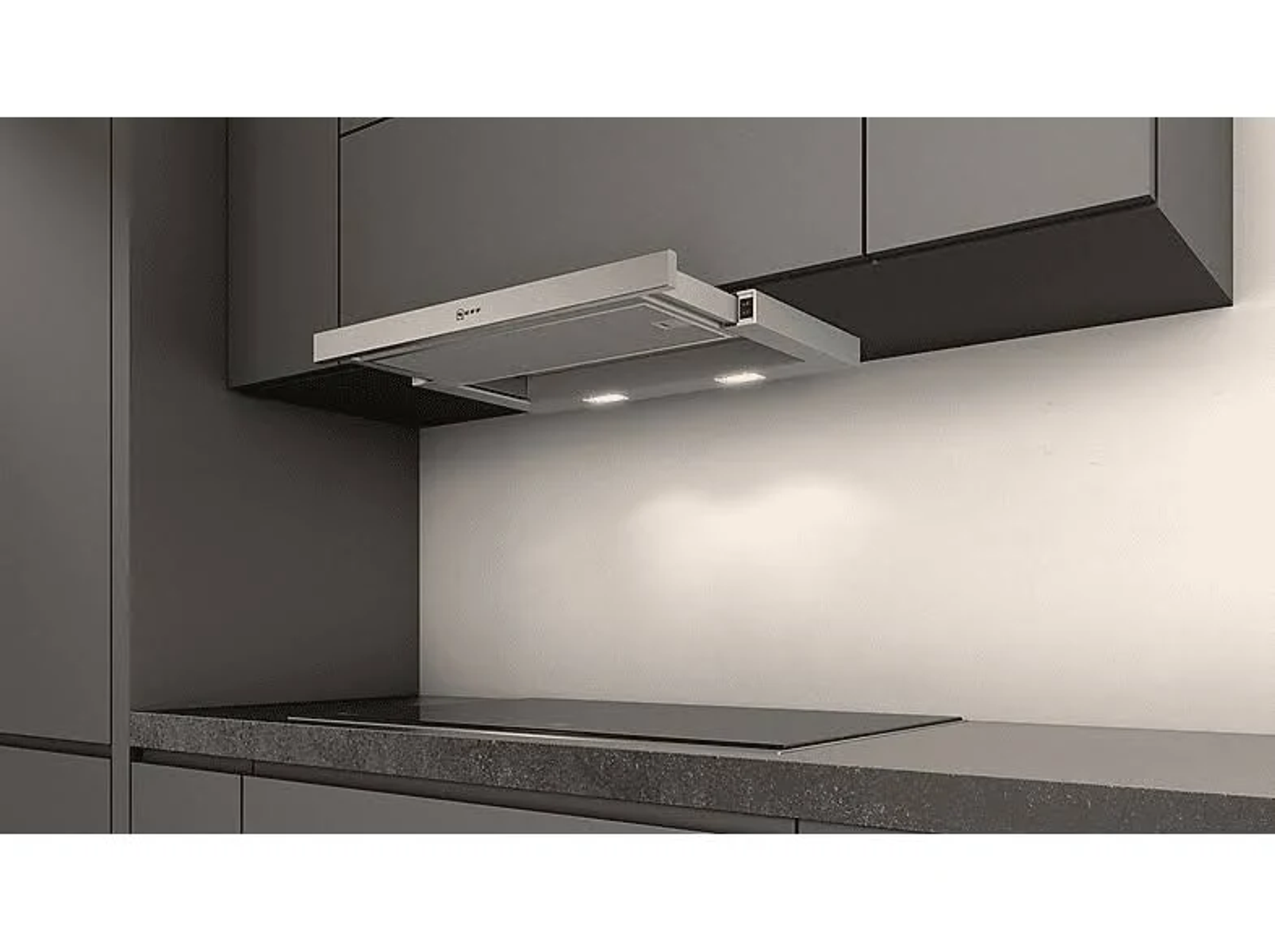 Campana extractora de cocina instalada encima de una encimera de vidrio negro. Es una cocina moderna.
