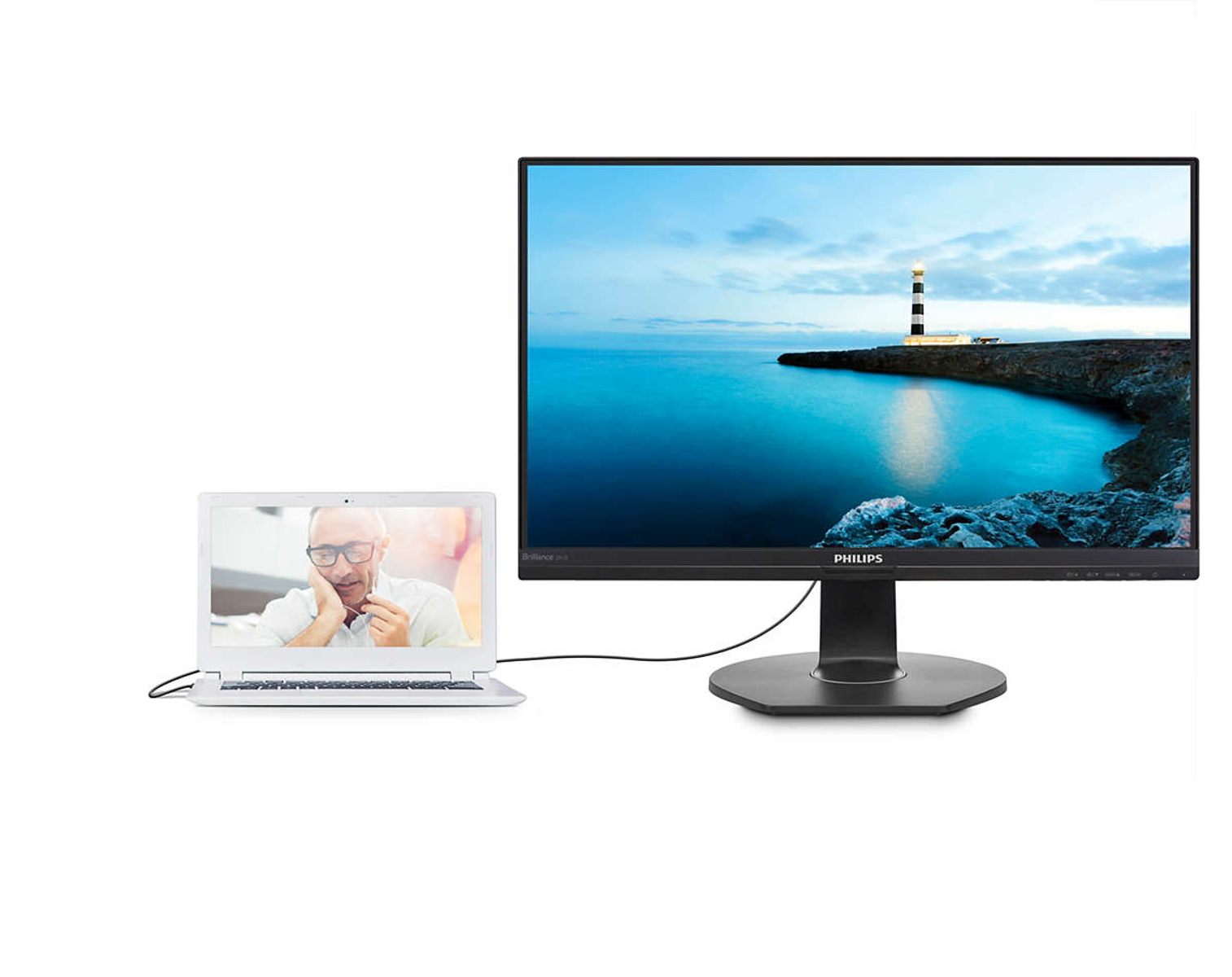 Una laptop conectada a un monitor que muestra una escena costera con un faro.