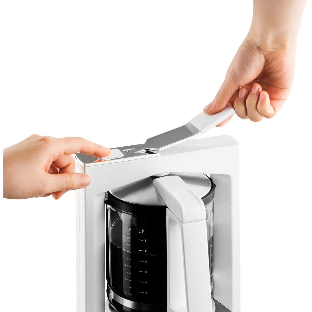 Ręce otwierają ekspres do kawy, biały i czarny, ze szklanym pojemnikiem.