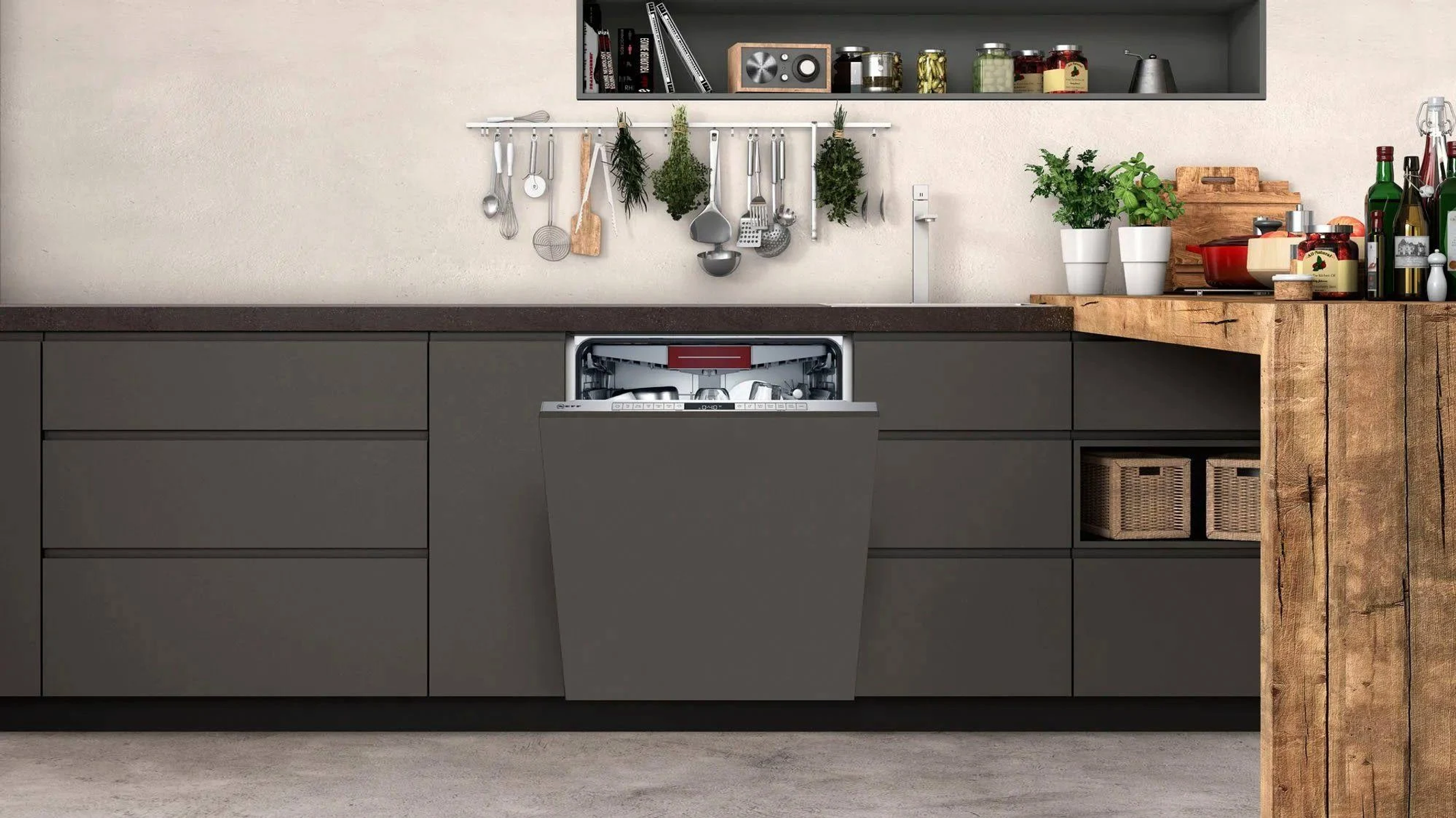 Modern kitchen with open dishwasher. Dark cabinets, wooden counter, utensils hanging, and plants on a light wall.