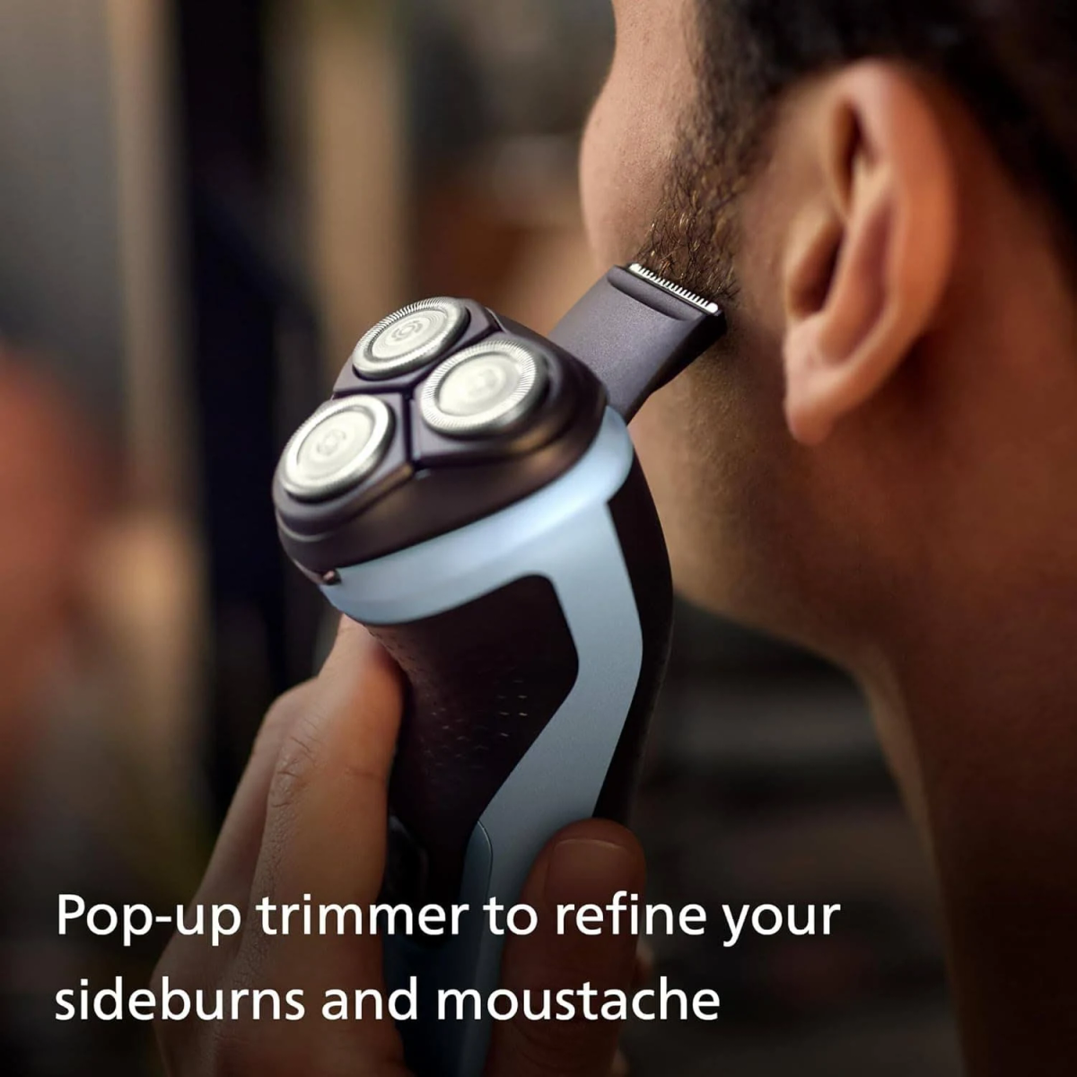 Mężczyzna używa golarki Philips, przycinając baki. Tekst: Trymer wysuwany do dopracowania baków i wąsów.