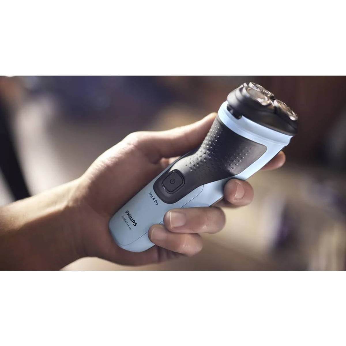 Dłoń trzymająca niebiesko-czarną golarkę Philips.