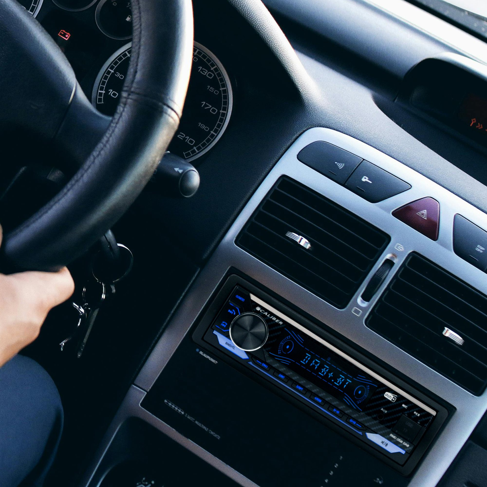 Auto-Innenraum. Hand am Lenkrad, Radioanzeige.