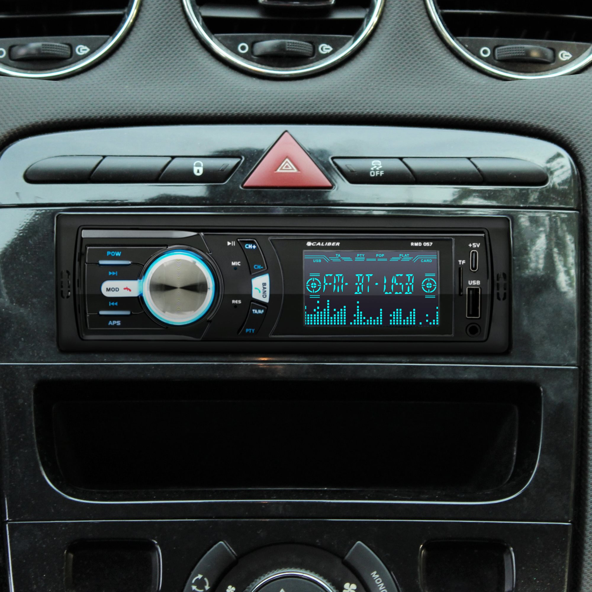 Car stereo head unit with a black and blue interface, buttons, and a display screen. The unit is in a car.
