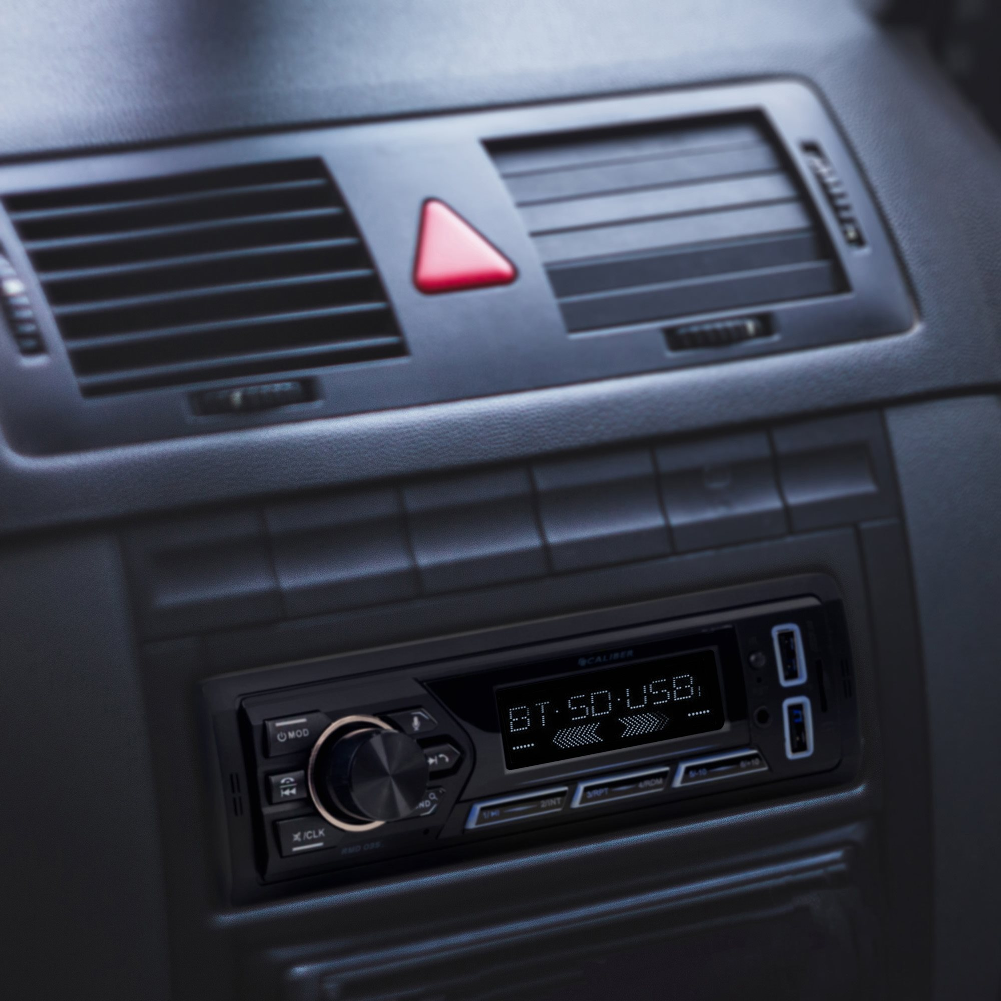 Car radio with display. Black with buttons and knob. Air vent and red triangle light above.