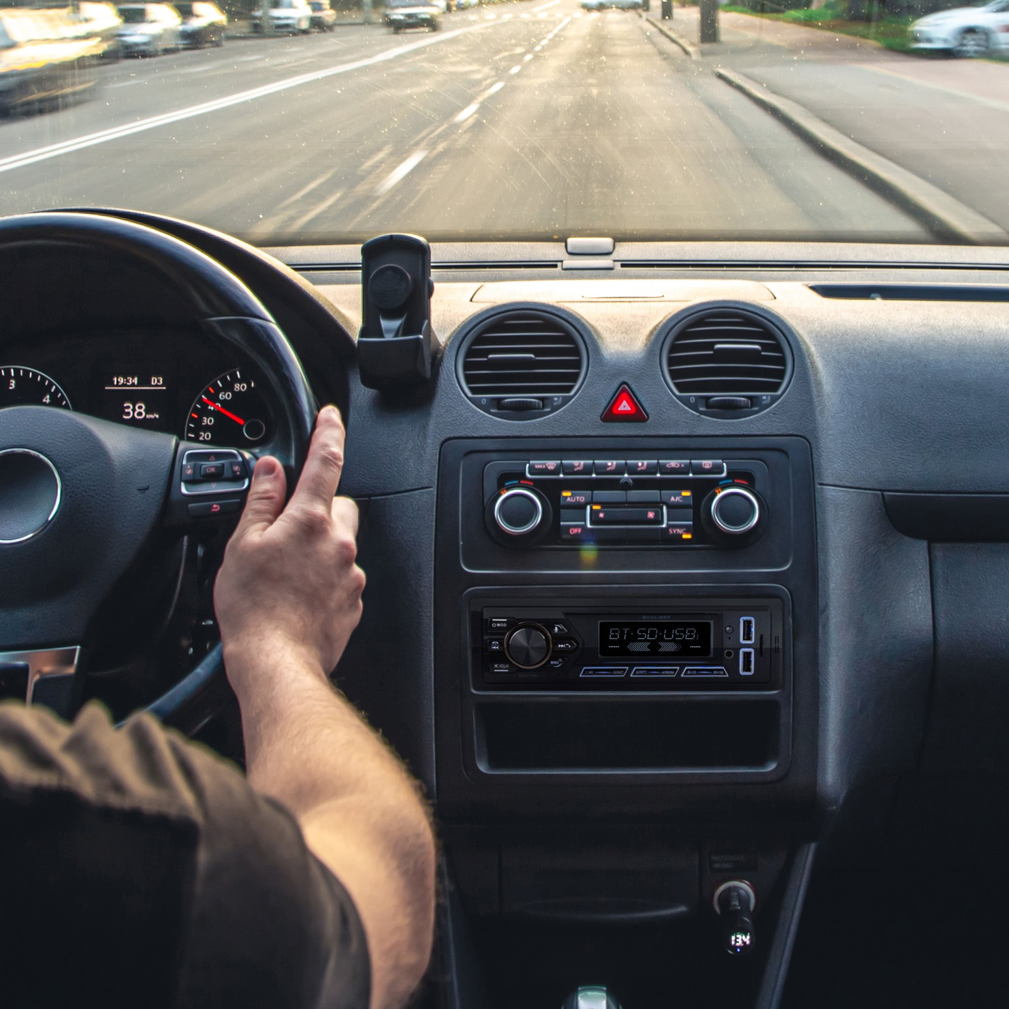 Driver's hands on steering wheel, dashboard with radio, and view of road ahead.