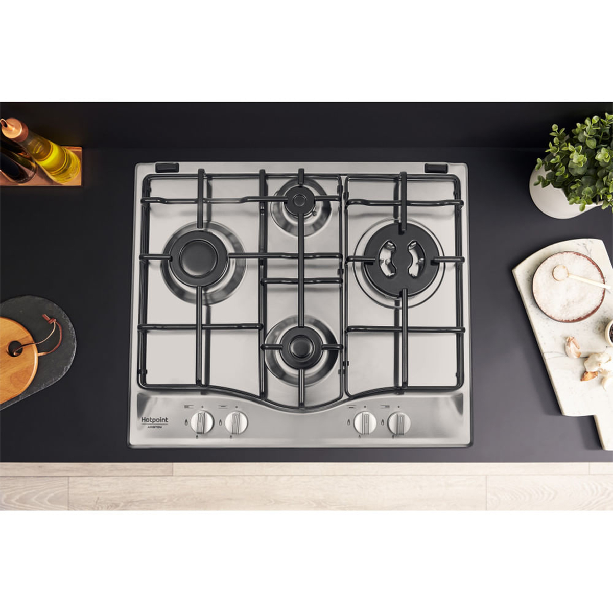 Widok z góry na płytę kuchenną ze stali nierdzewnej z czterema palnikami i czarnym blatem.