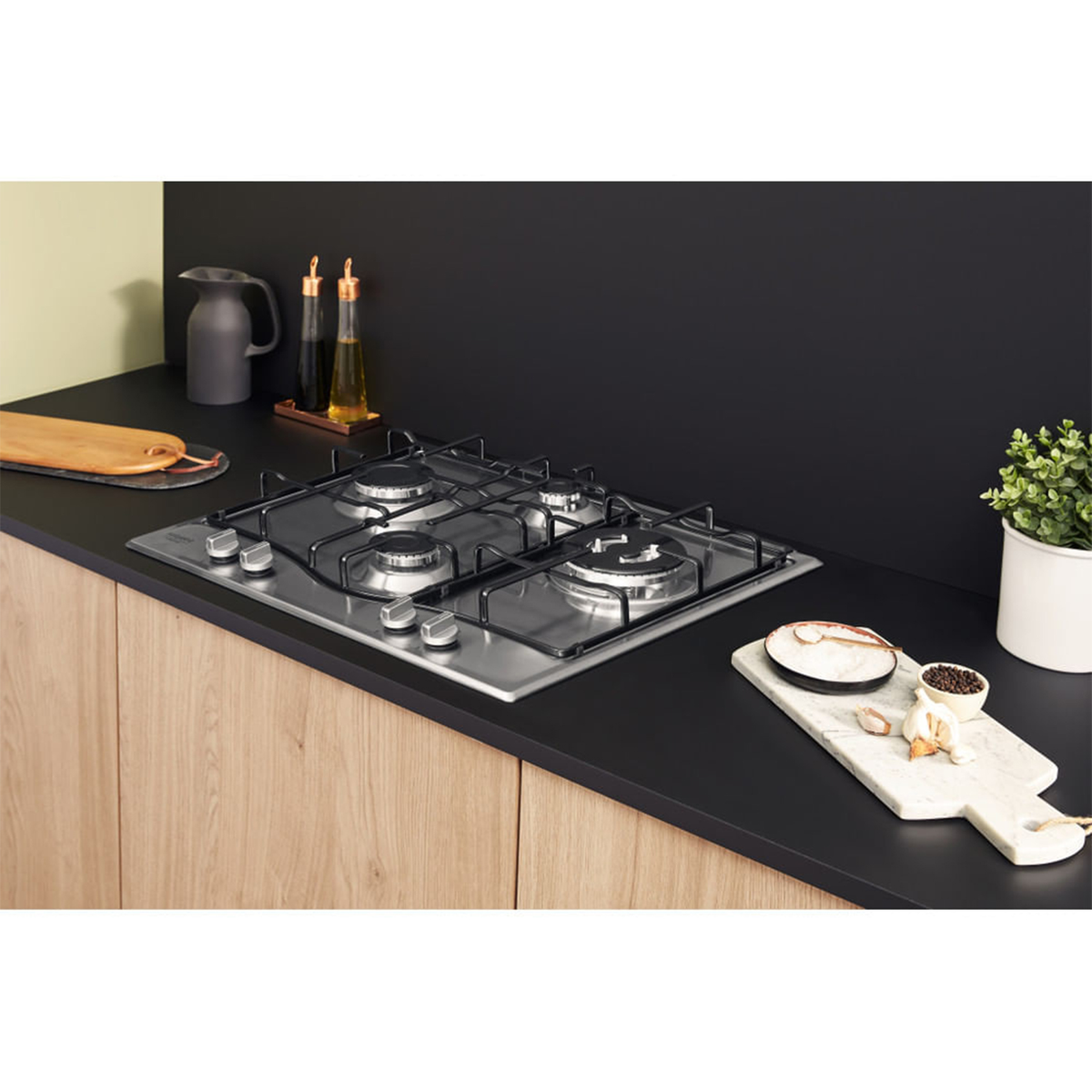 Płyta kuchenna ze stali nierdzewnej z czterema palnikami na blacie kuchennym z drewnianymi szafkami.