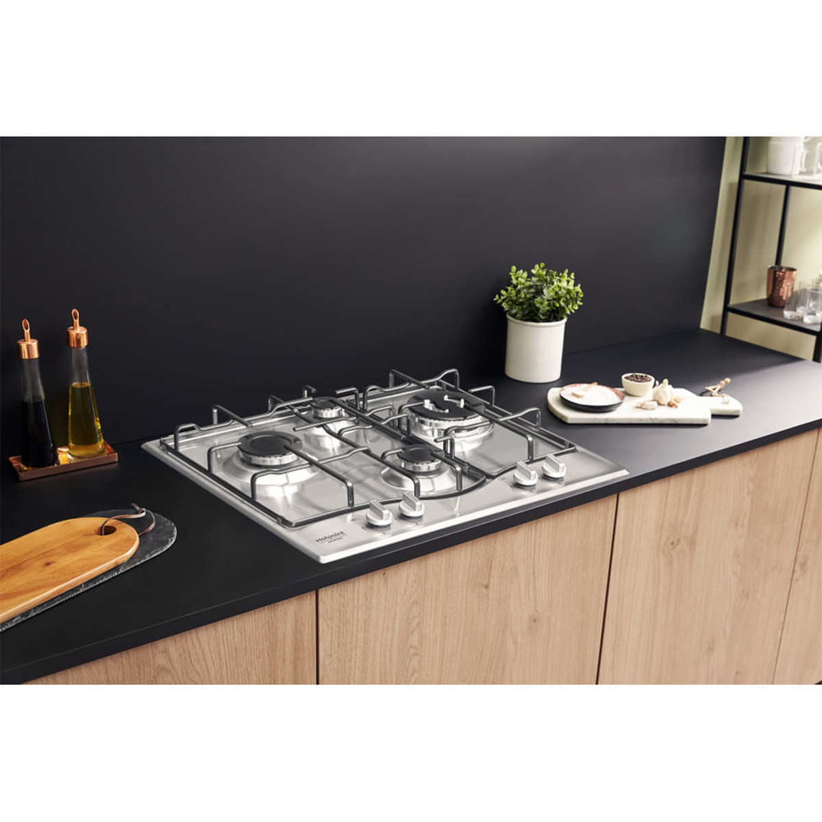 Wbudowana płyta gazowa z czterema palnikami na czarnej powierzchni, z drewnianymi szafkami poniżej.