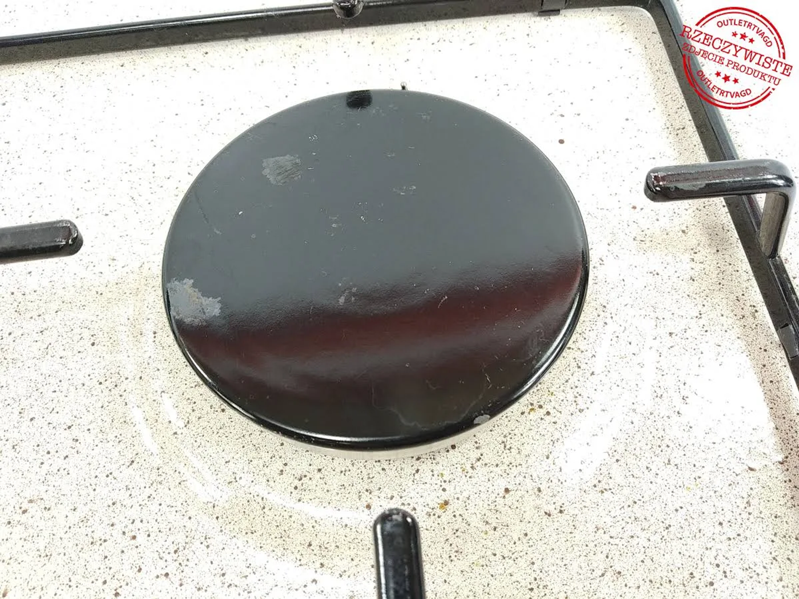 Zbliżenie na czarny palnik kuchenki gazowej z czarną okrągłą nasadką palnika.