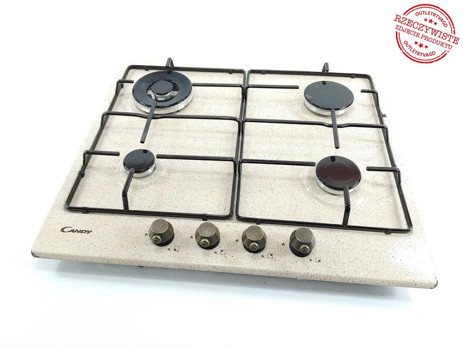 Kuchenka gazowa Candy z czterema palnikami, pokrętłami i białą, nakrapianą powierzchnią.