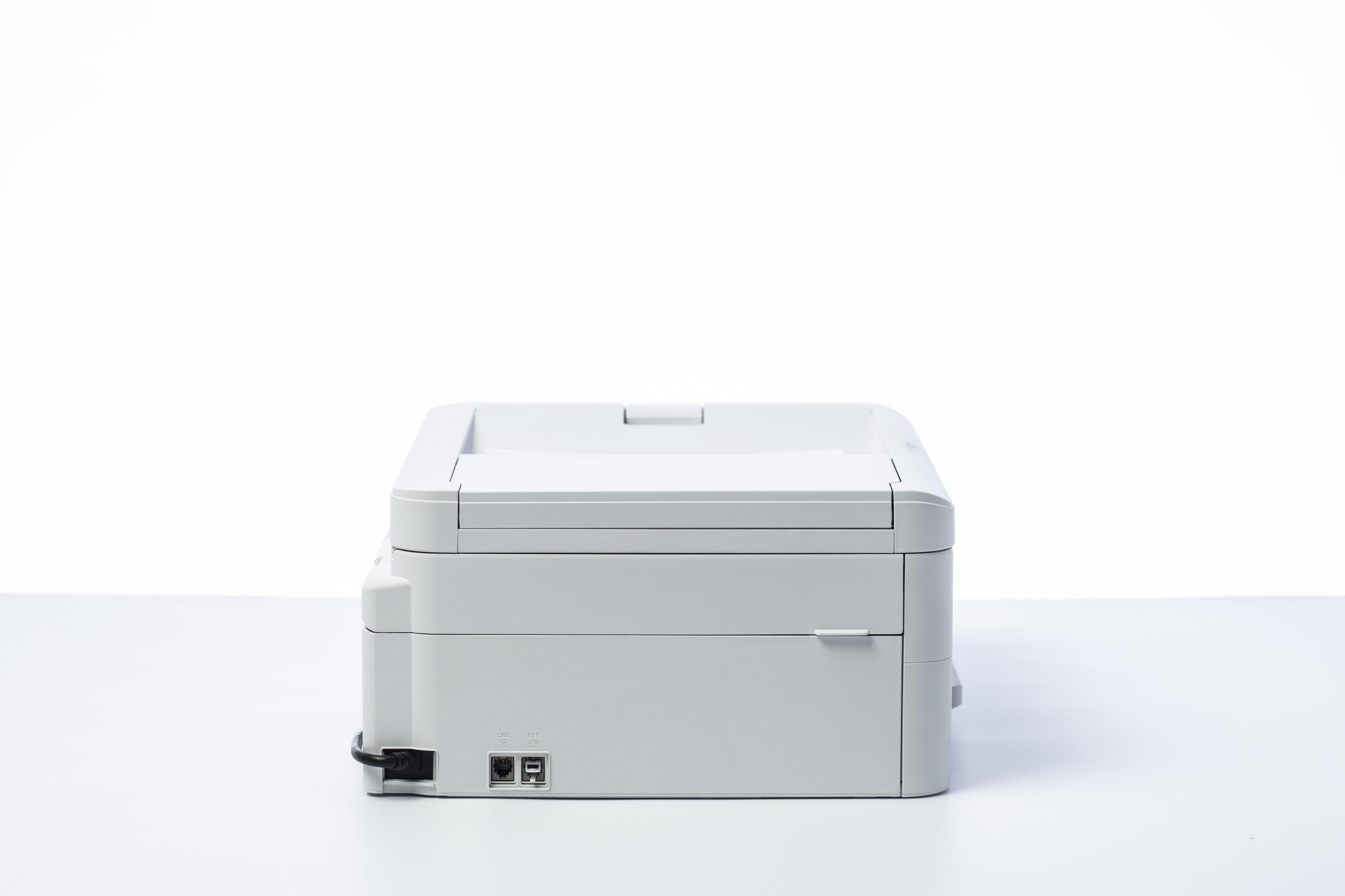 Biała drukarka, widok z boku, z otwartą górną pokrywą. Białe tło.