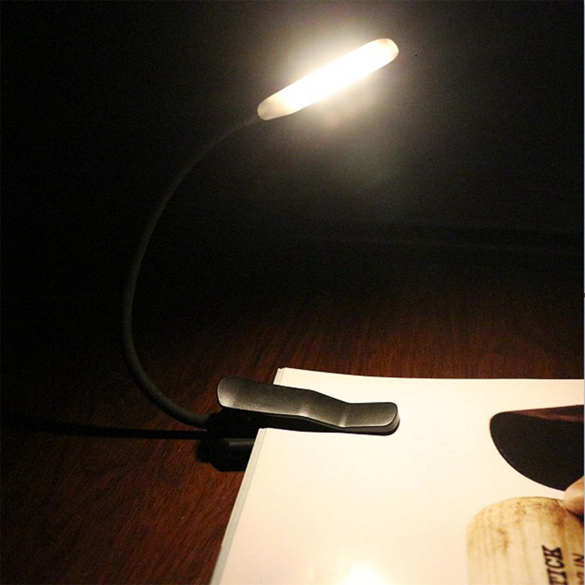 Schreibtischlampe mit Clip. Das Licht ist an und scheint auf ein Buch.