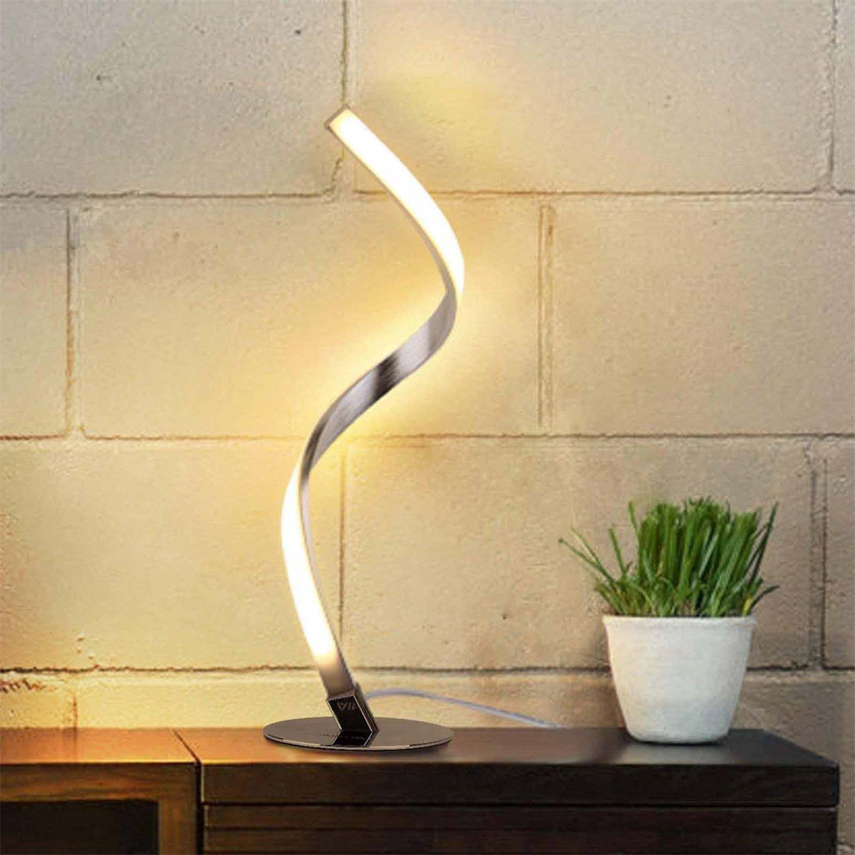 Eine moderne silberne und weiße Lampe. Sie hat einen gebogenen, beleuchteten Schaft und steht auf einem Holztisch.