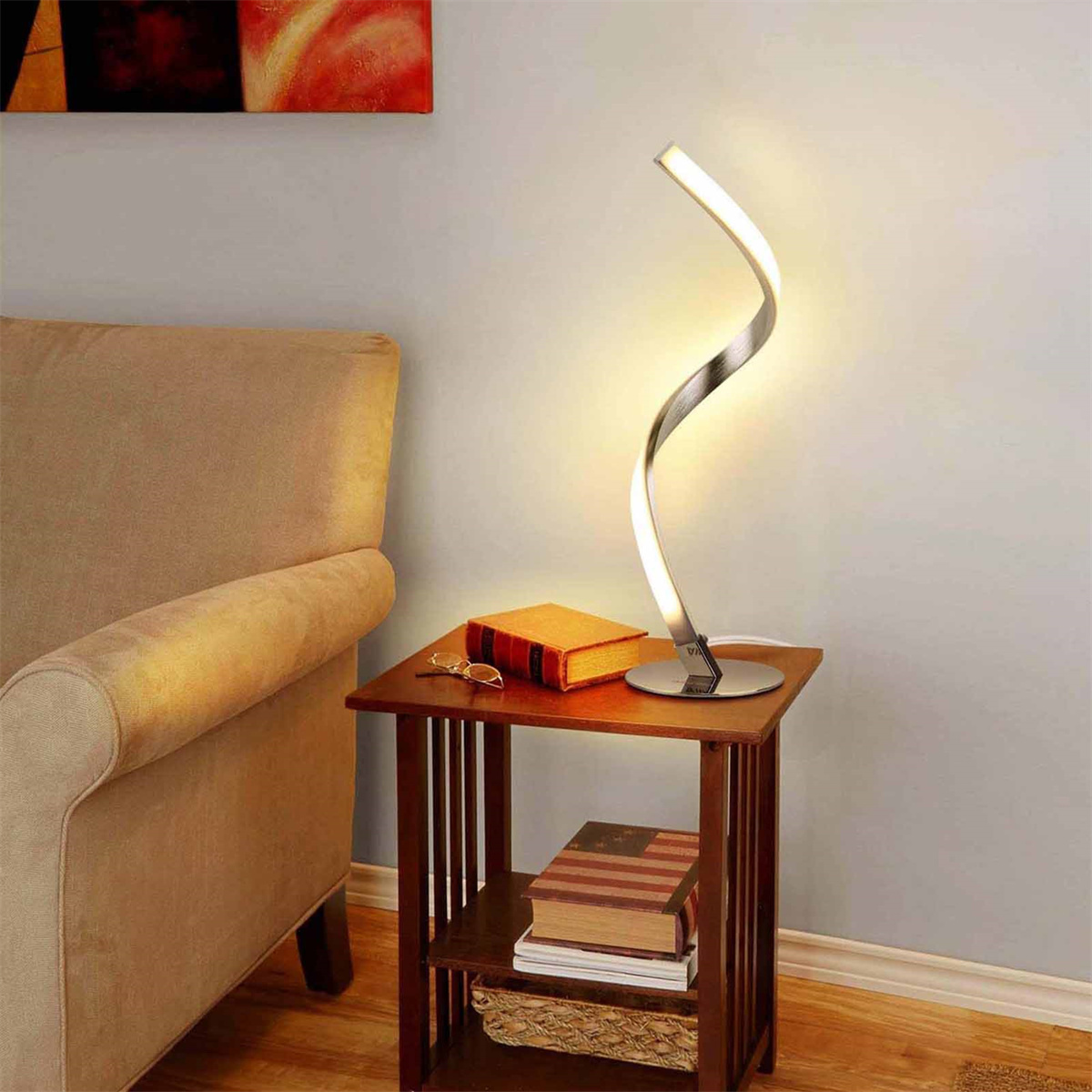 Eine moderne silberne und weiße Lampe auf einem kleinen Holztisch mit Büchern und einem Stuhl.