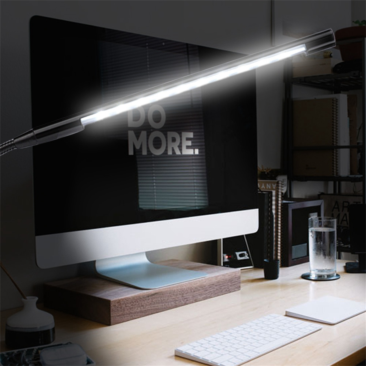 Eine beleuchtete Schreibtischlampe über einem Computermonitor mit 'DO MORE' und einer Tastatur.
