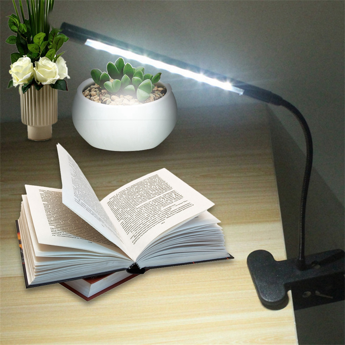Eine helle LED-Schreibtischlampe beleuchtet ein offenes Buch auf einem Schreibtisch. Pflanzen und Blumen sind ebenfalls da.