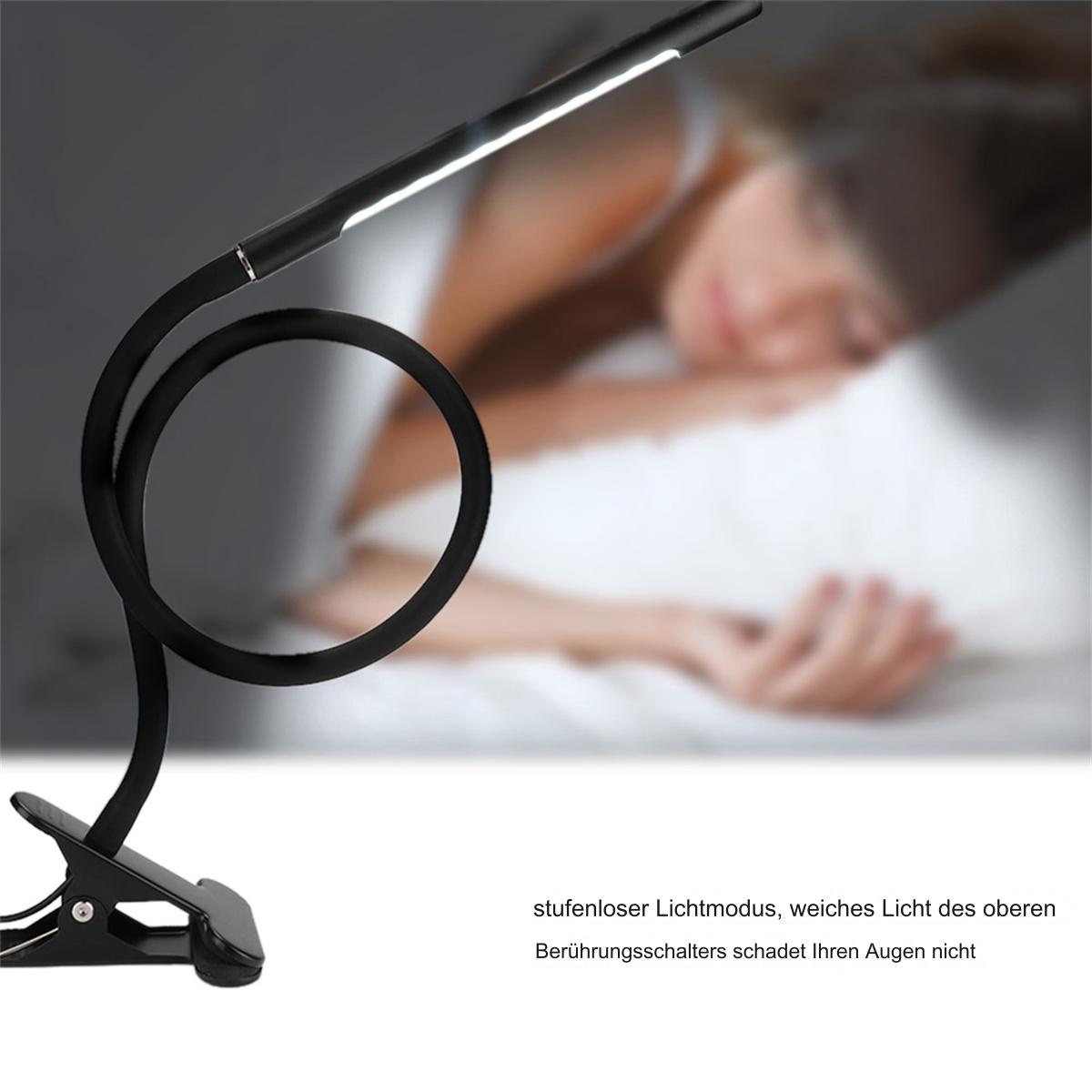 Schwarze flexible Schreibtischlampe mit schlafender Person im Hintergrund.