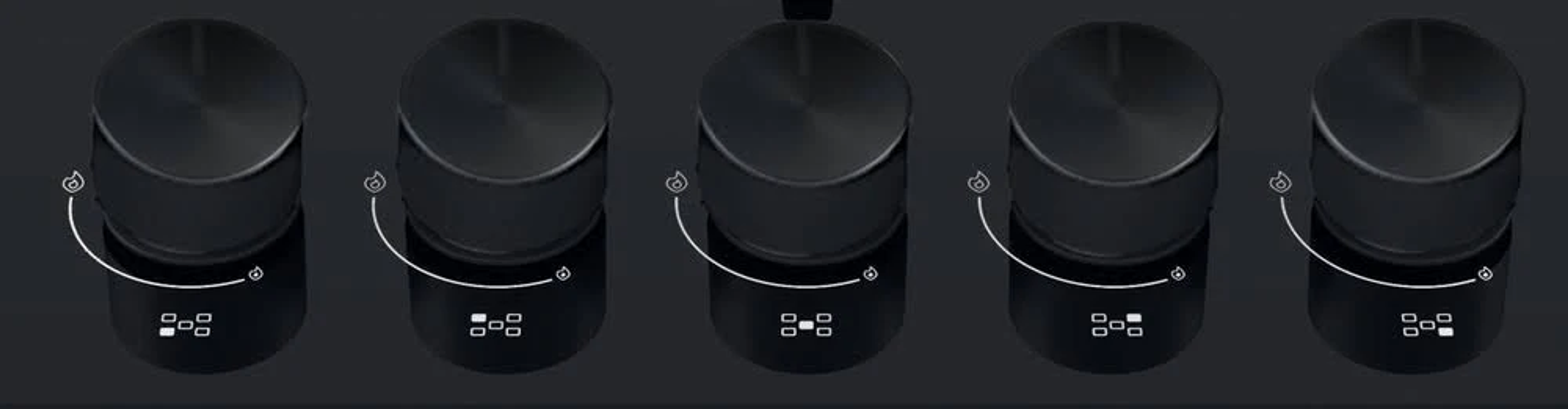 Czarne pokrętła na kuchence, z białymi wskaźnikami i czarnym tłem.