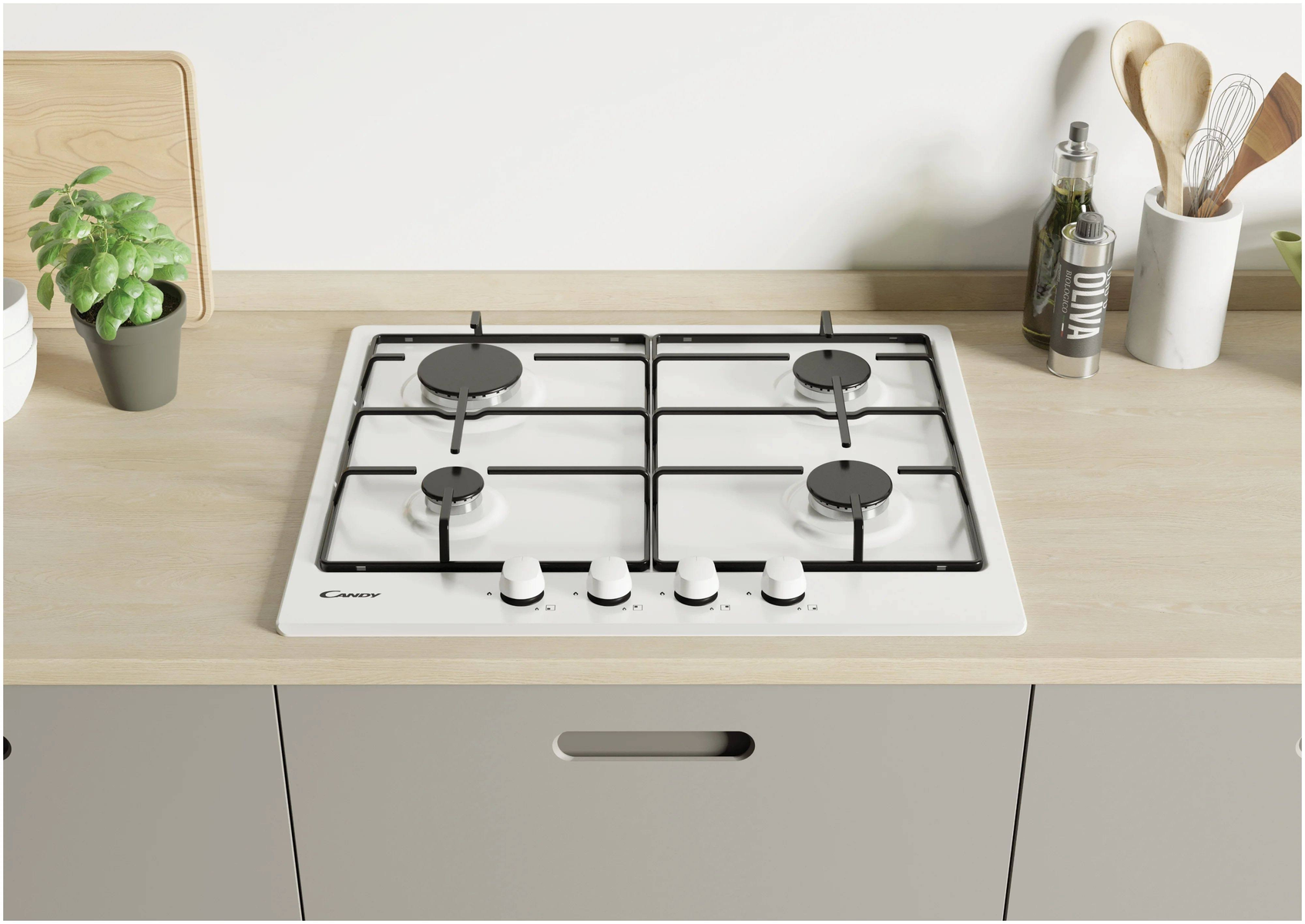 Biała płyta gazowa na drewnianym blacie. Cztery palniki, pokrętła poniżej. Drewniana łyżka i roślina.