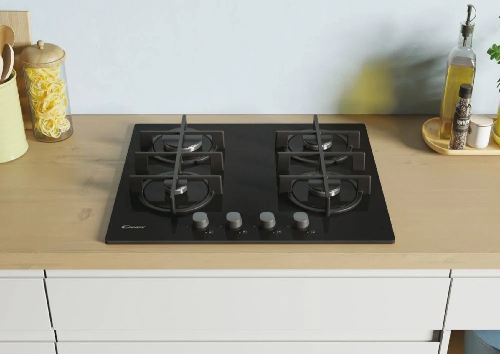 Czarna płyta grzewcza z czterema palnikami i srebrnymi pokrętłami na drewnie.