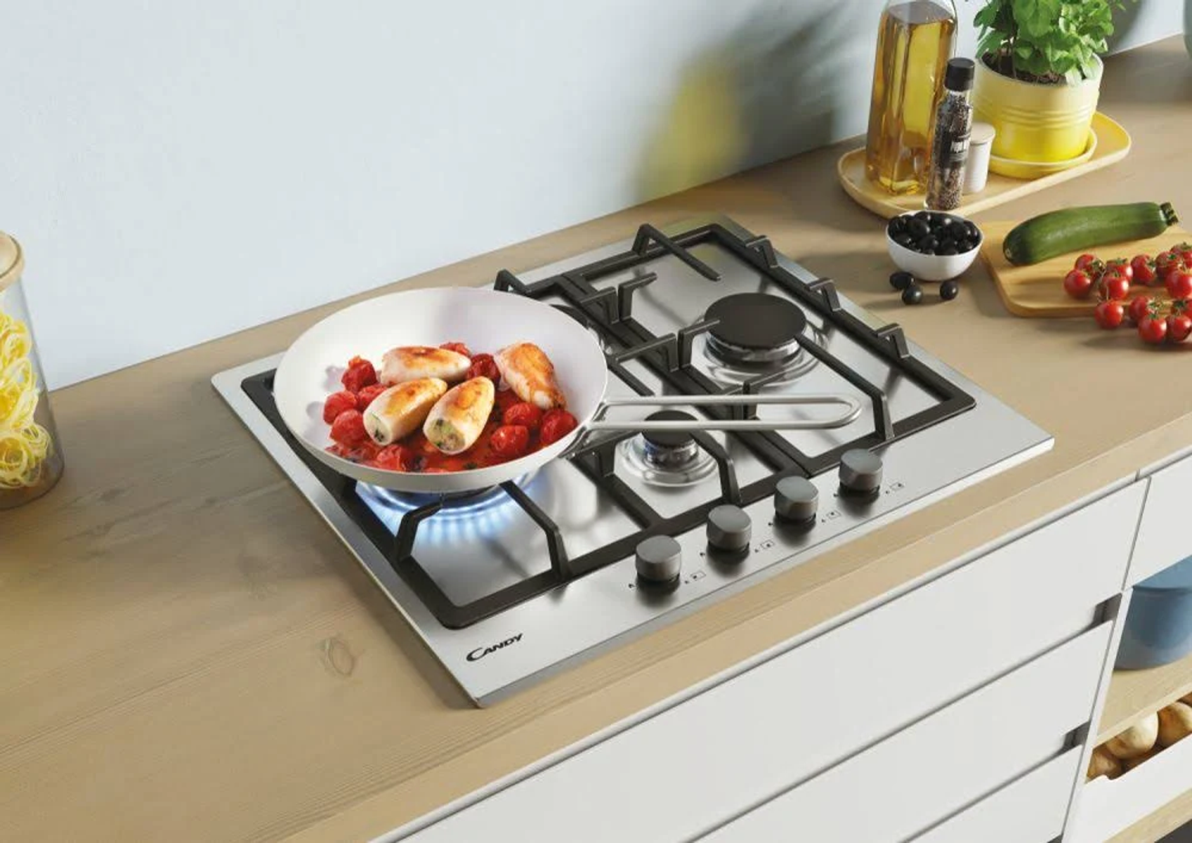 Płyta grzejna z patelnią z jedzeniem, olejem, pomidorami i cukinią.