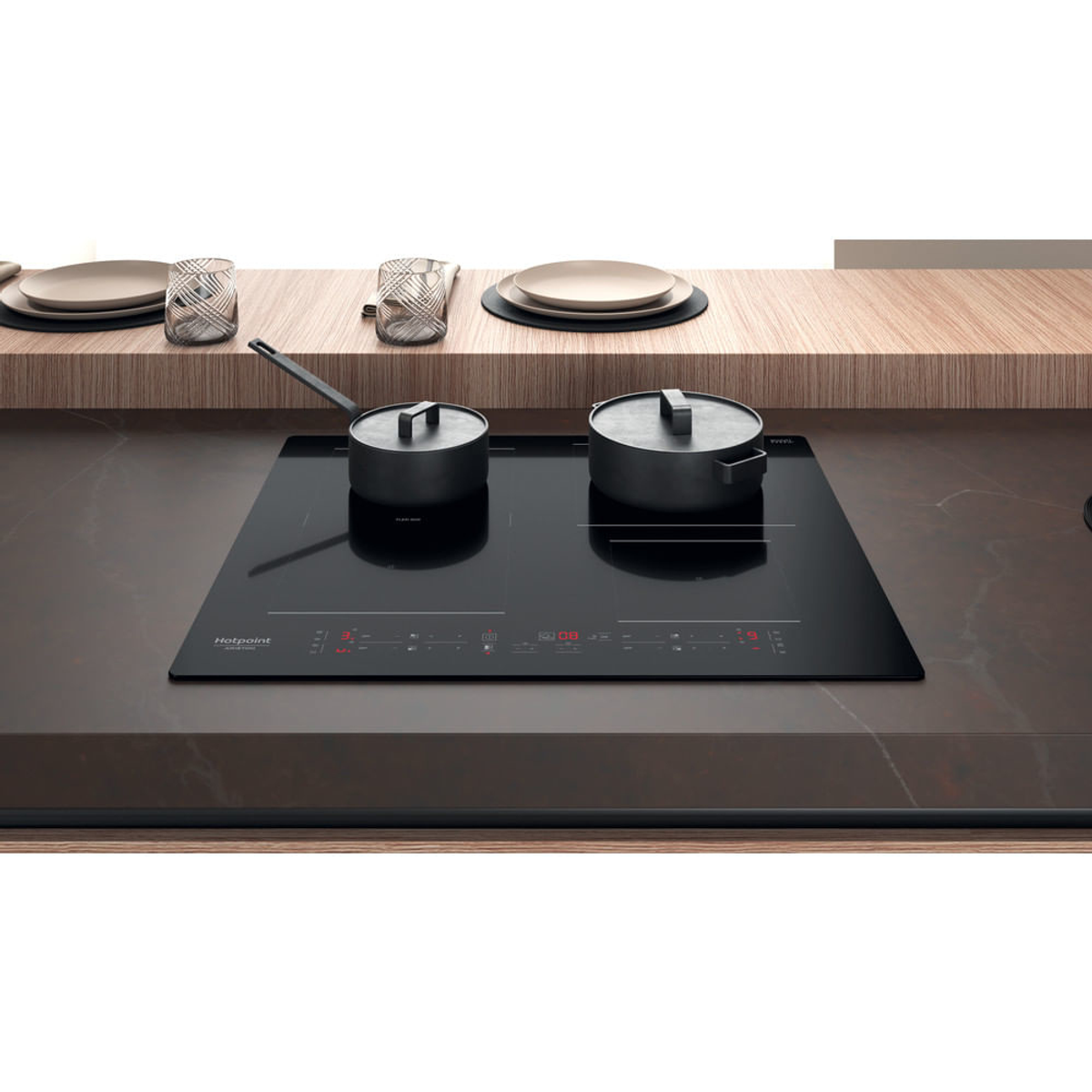 Czarna płyta indukcyjna z dwoma garnkami na brązowym blacie.