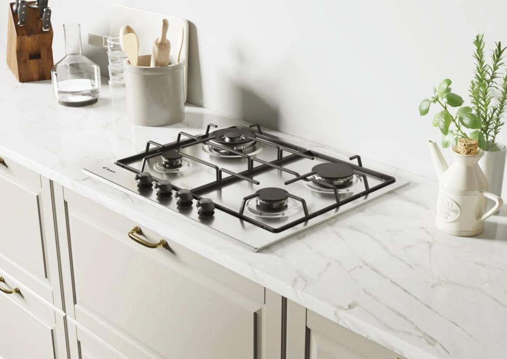 Płyta gazowa ze stali nierdzewnej z czterema palnikami, na białym blacie.
