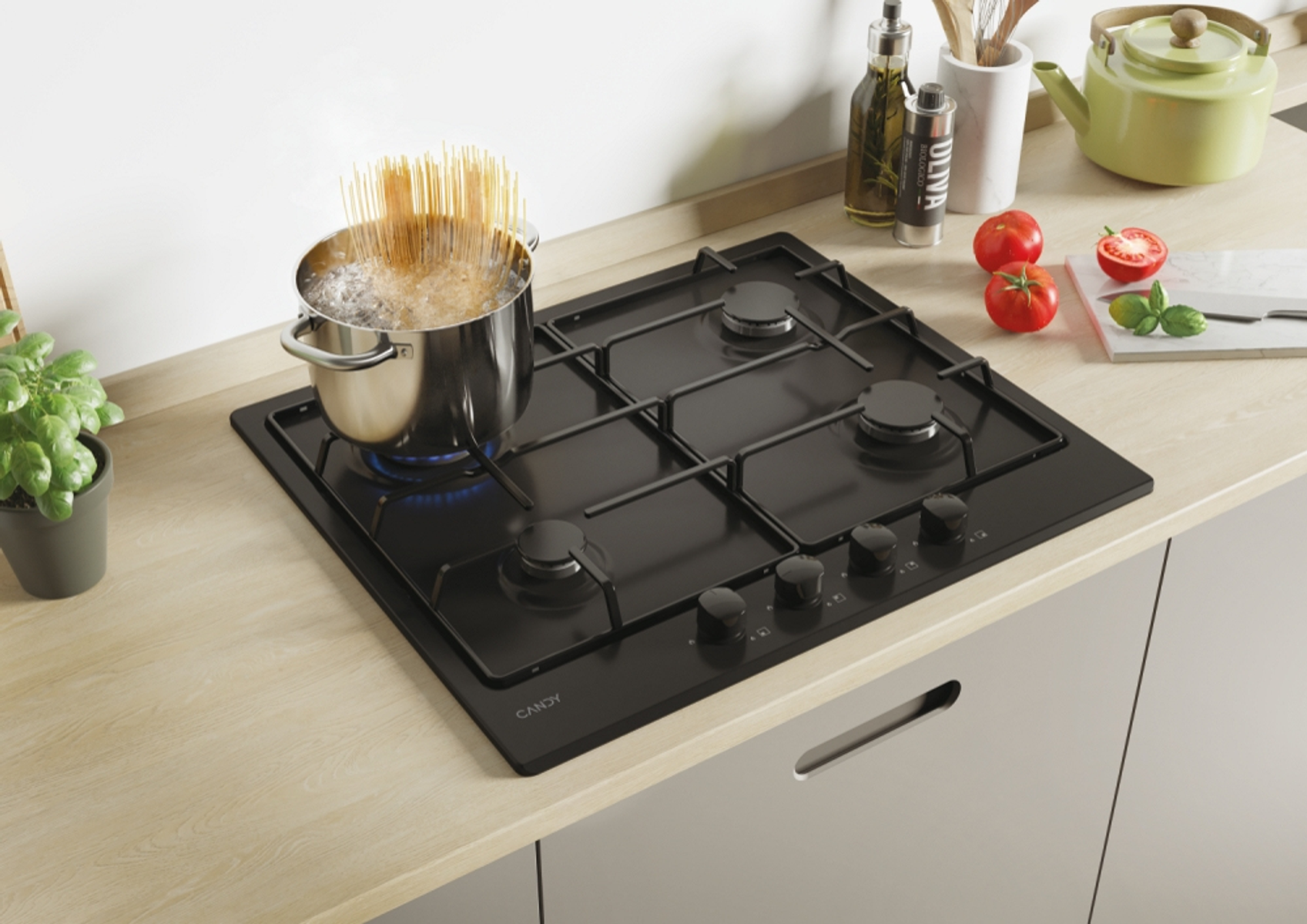 Scena kuchenna. Czarna płyta gazowa z garnkiem wrzącej wody. Pomidory, olej i bazylia w pobliżu.