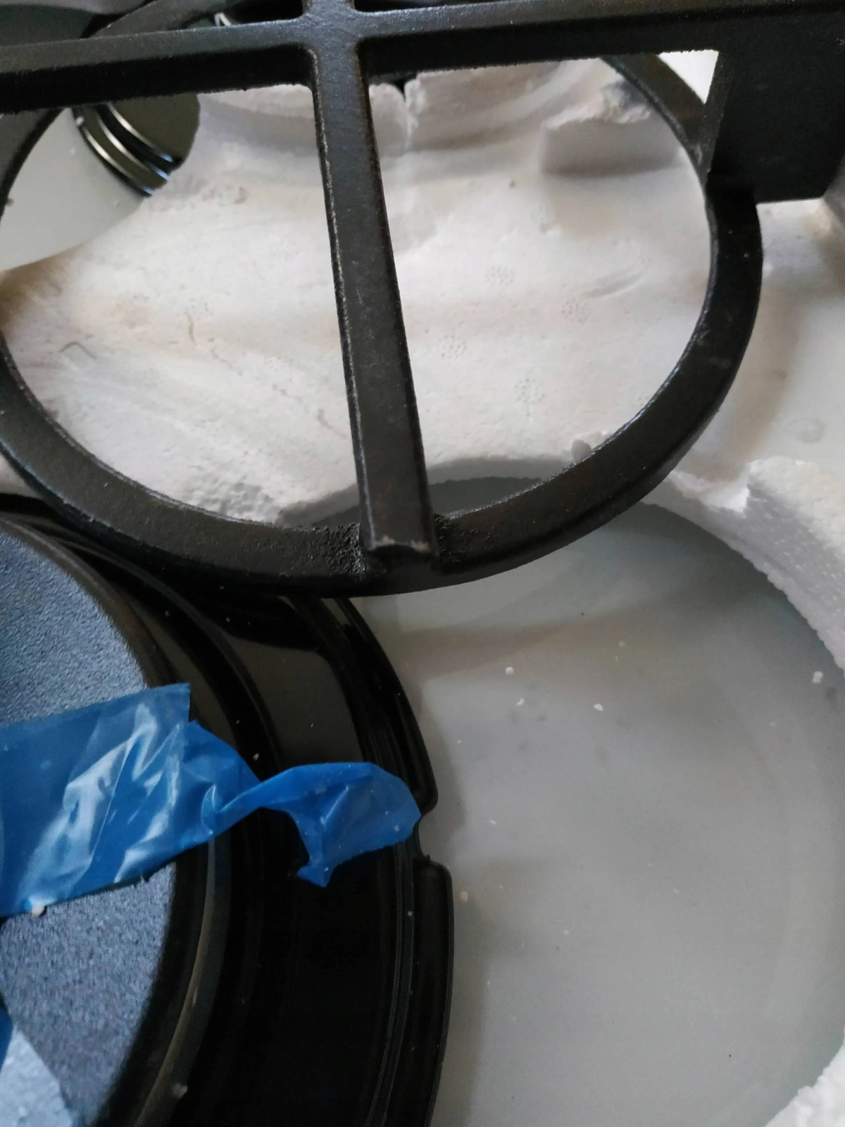 Wnętrze bębna pralki. Widoczna czarna metalowa krata i niebieska plastikowa część.