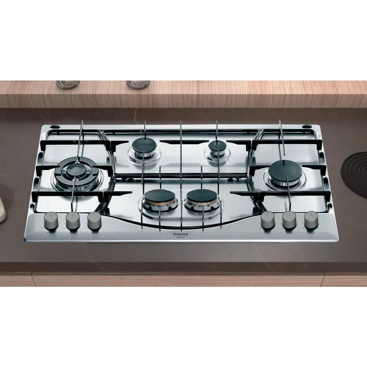 Widok z góry na stalową płytę gazową Hotpoint. Pięć palników i pokrętła sterowania.
