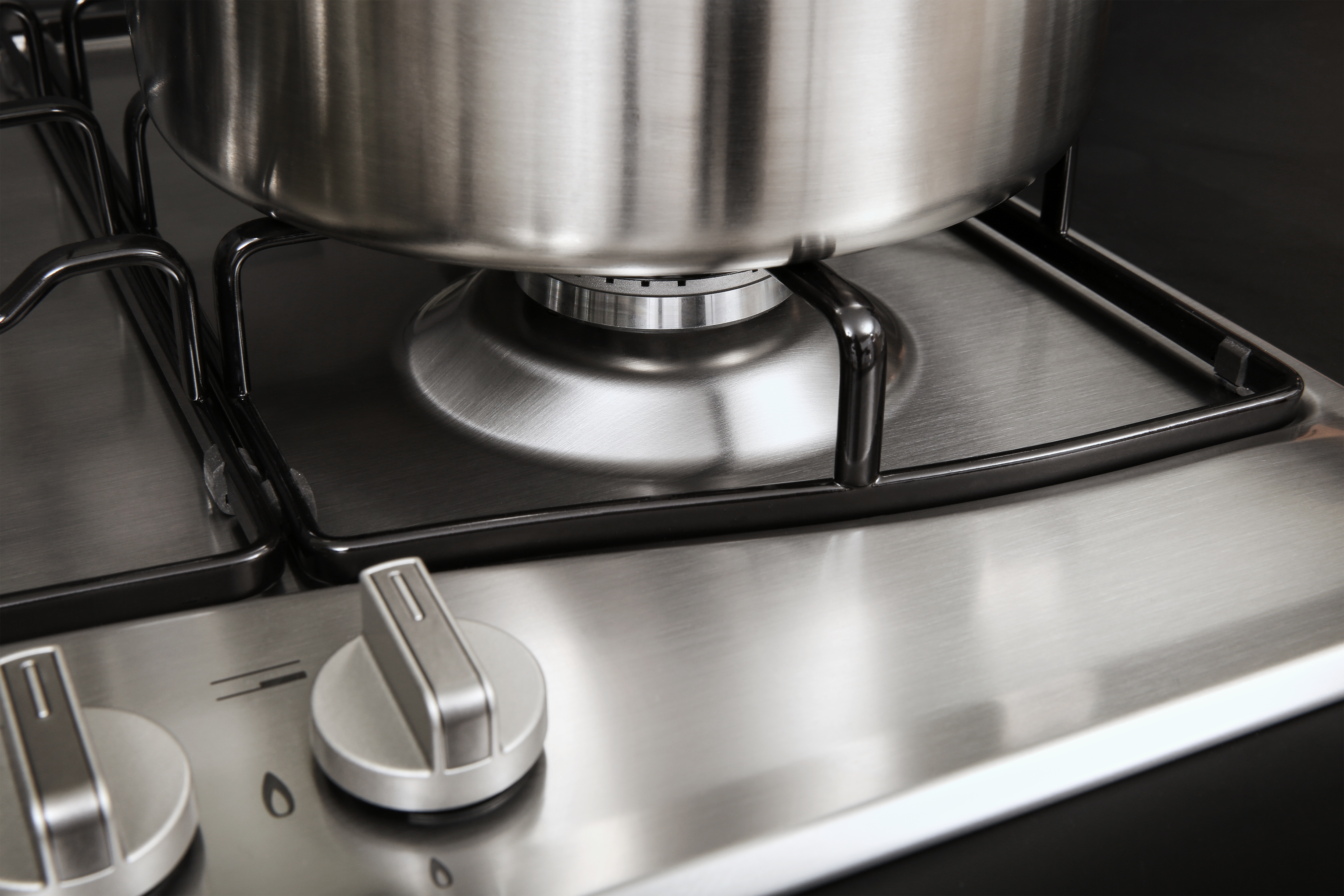 Zbliżenie płyty gazowej ze stalową powierzchnią i garnkiem.