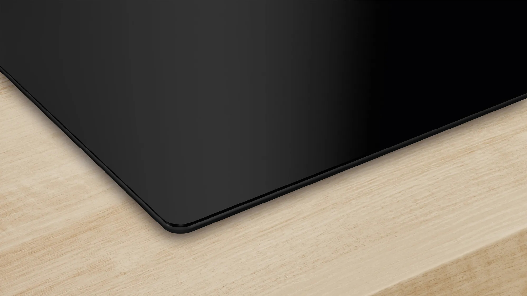 Czarna płyta grzewcza, zbliżenie. Powierzchnia jest gładka i odbijająca światło.